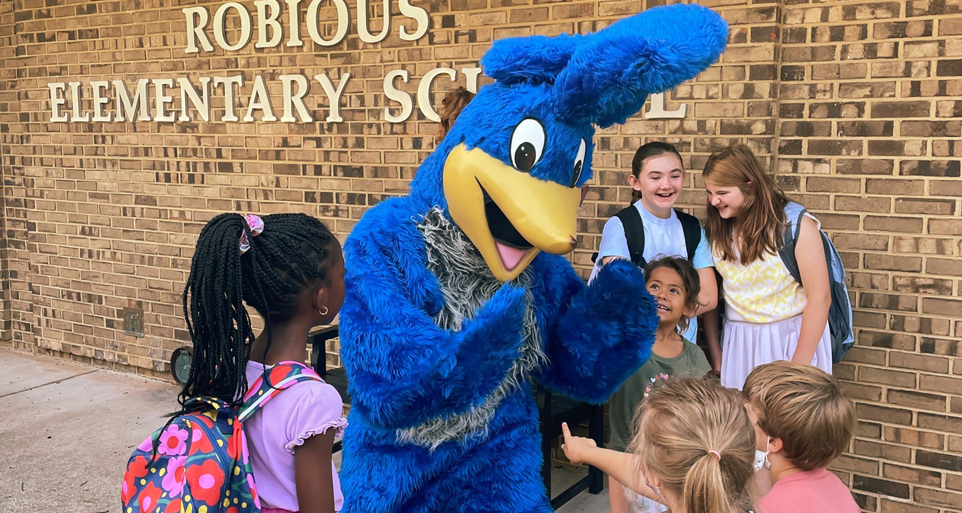 Mascot with students outside.