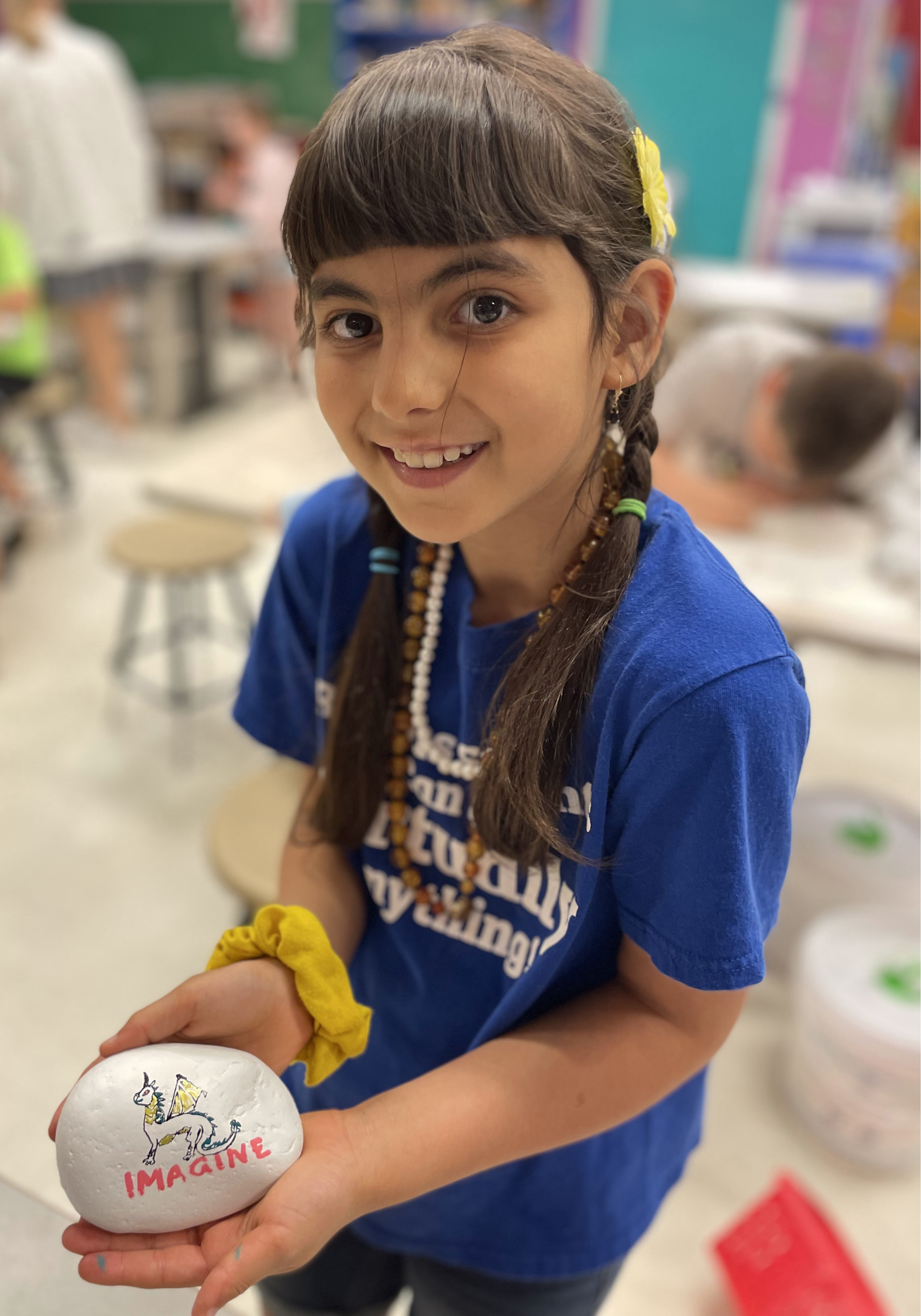Female student holding up a rock that she painted.