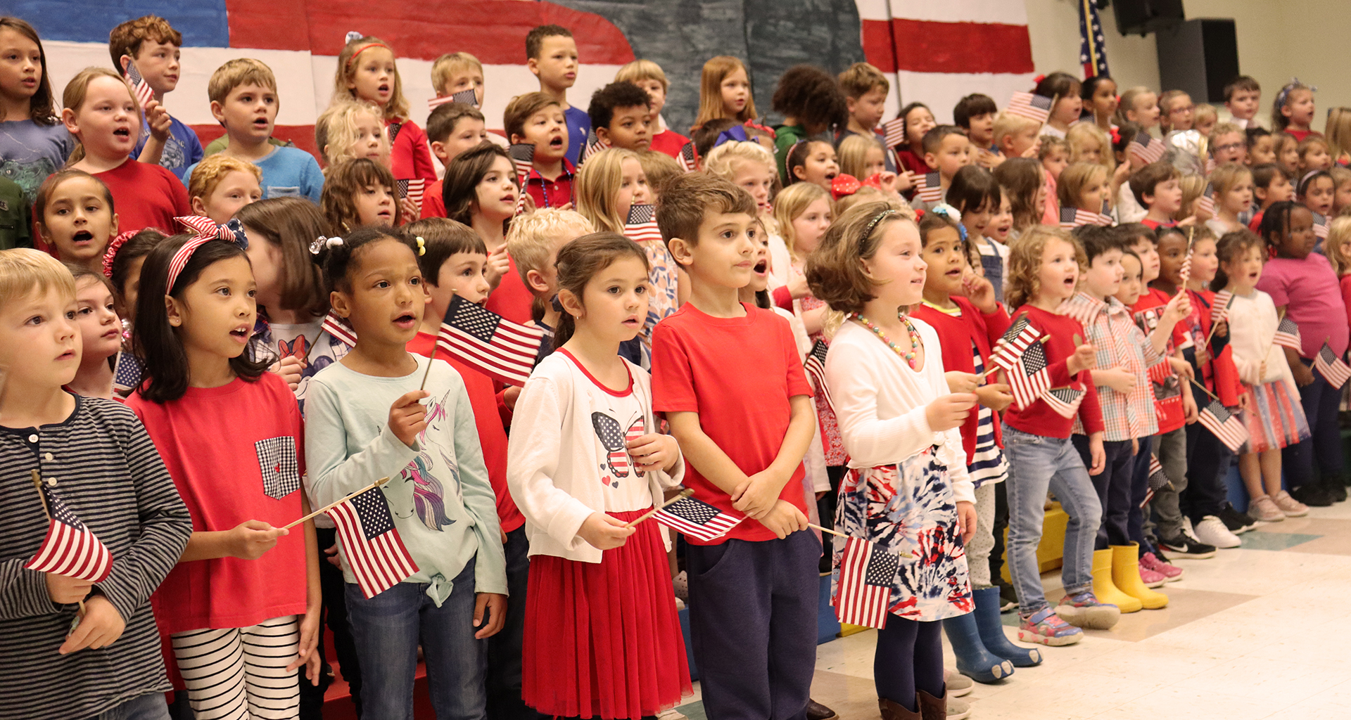 Large group of students standing on a stage singing for Veteran's Day