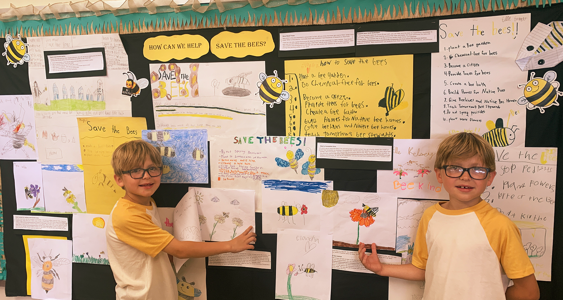 Two students standing in front of wall full of student projects.