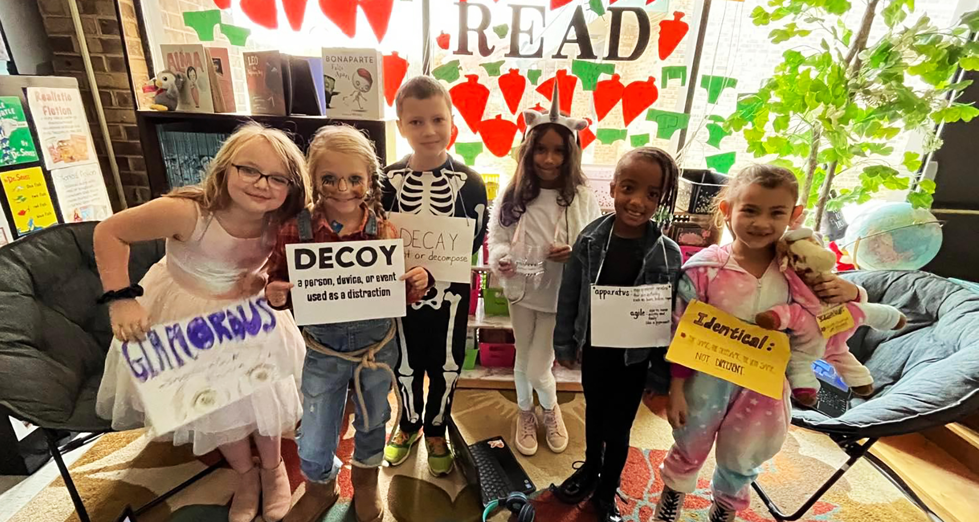 Students holding up signs they made in the reading area of the classroom.