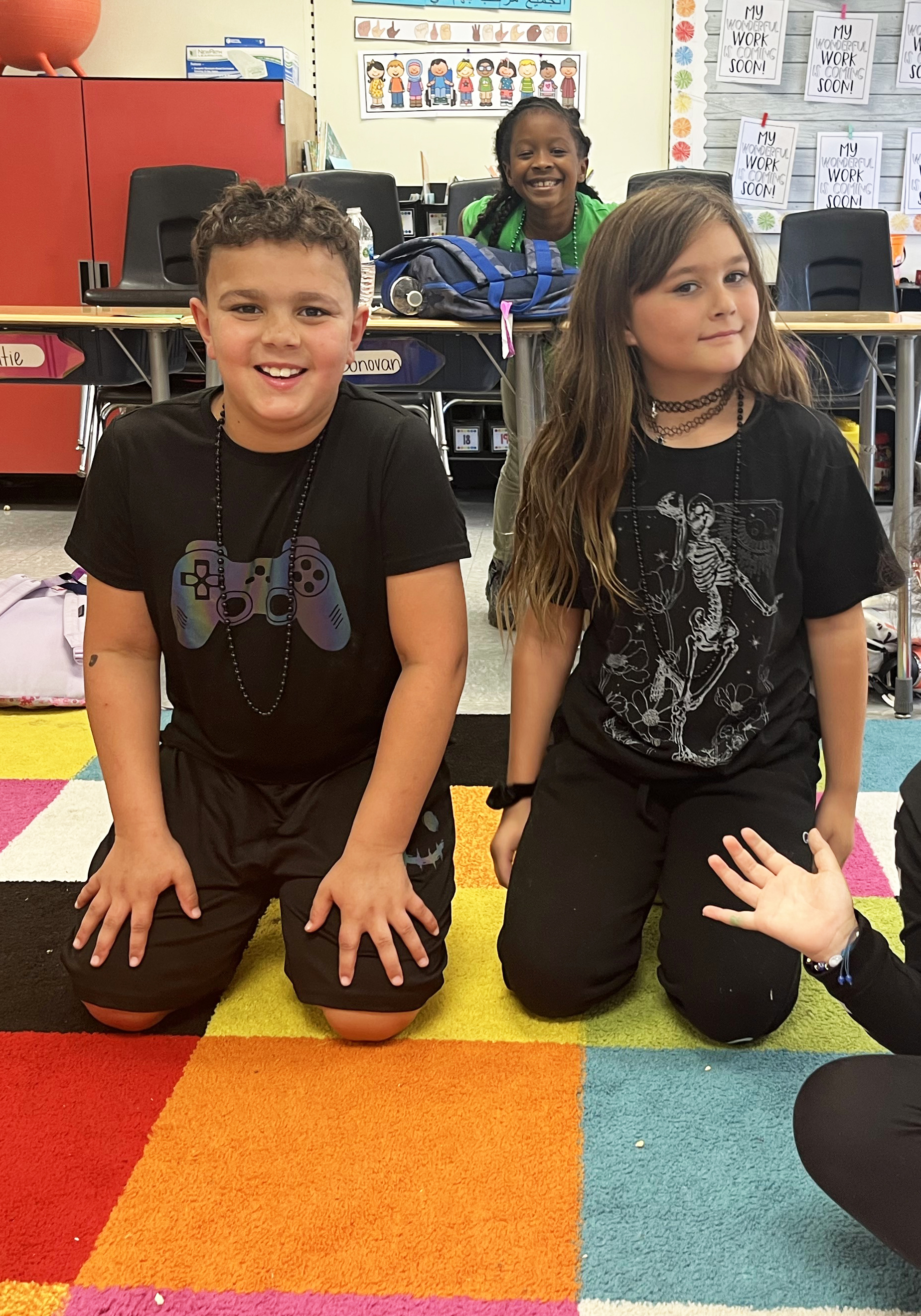 Two students pose for a photo in class as they kneel down