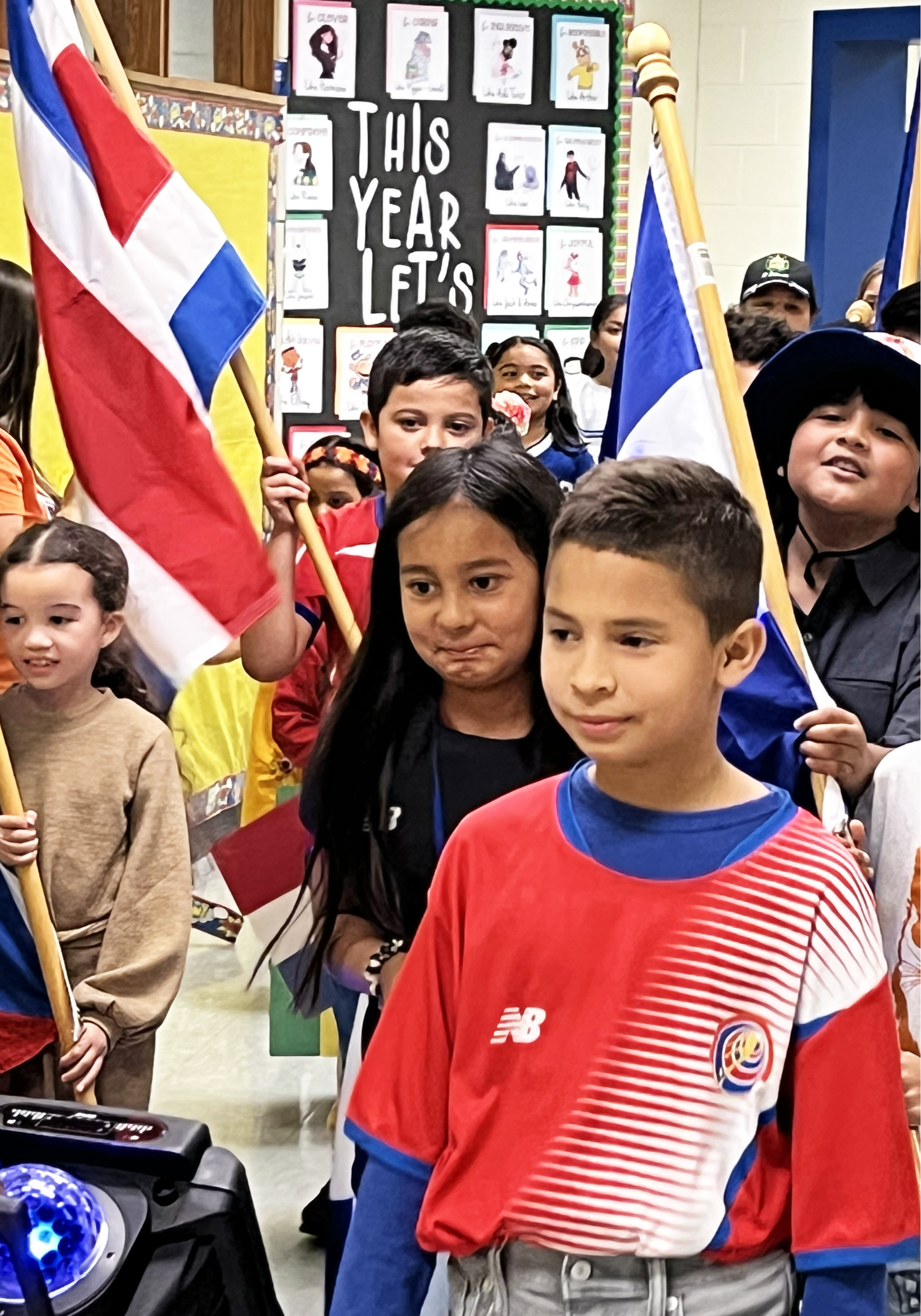A group of students walking down the hallway as some hold flags
