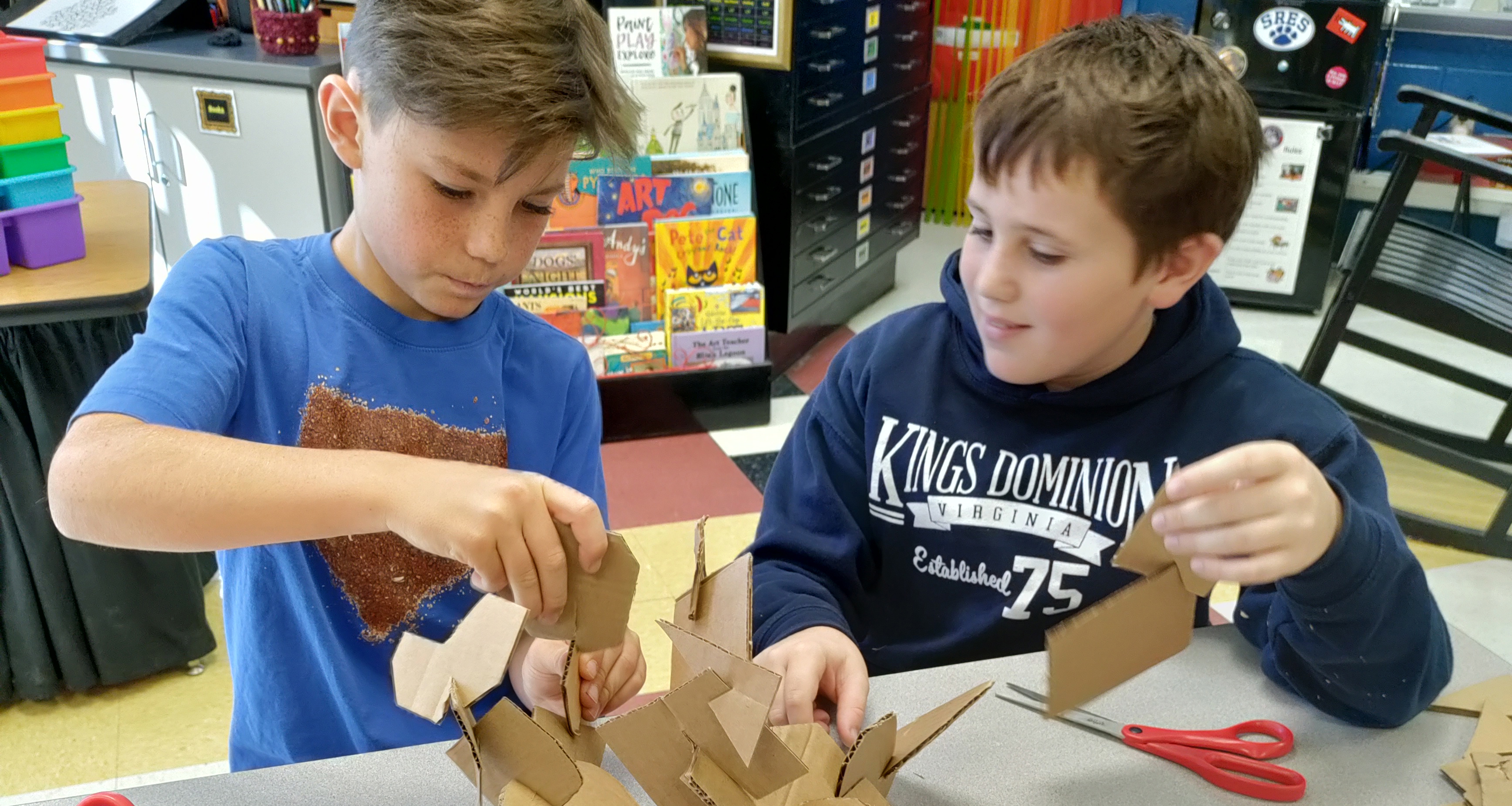 Two students working on a structure made of cardboard pieces