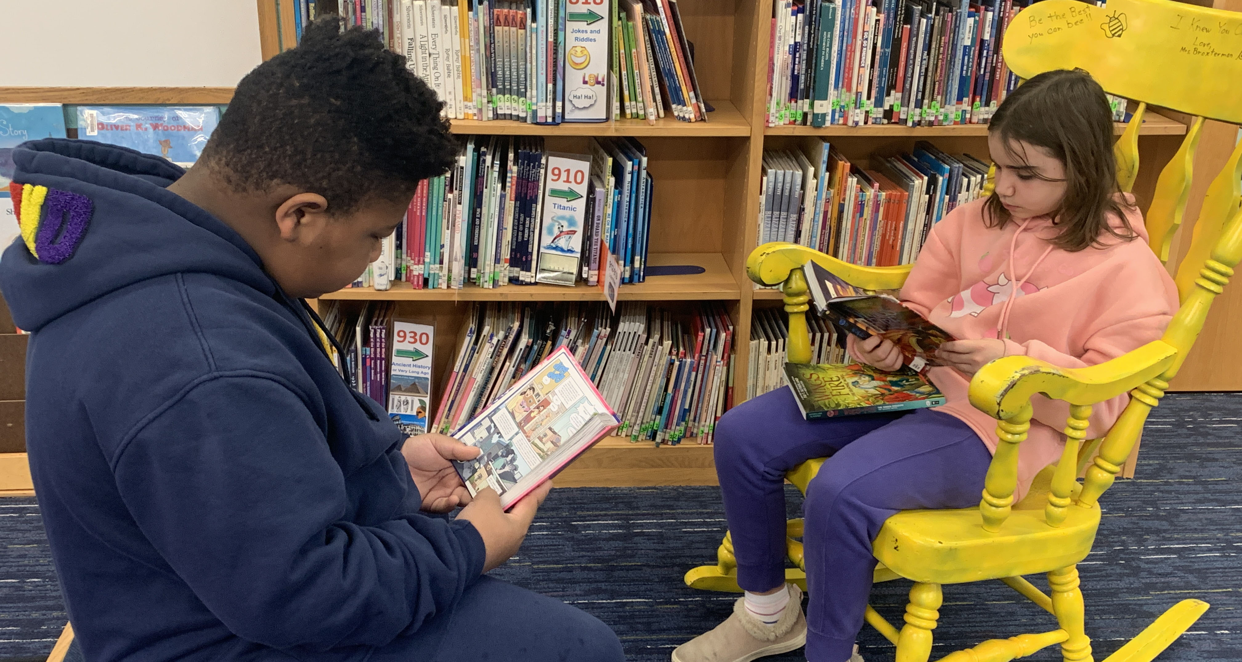 Two students reading books at the school library