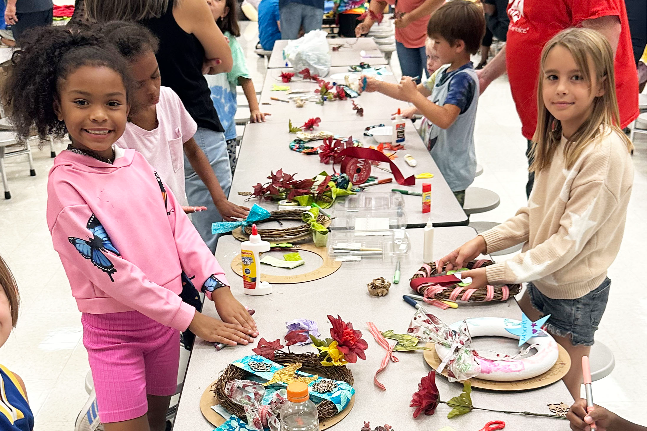 Two girls smiling, building wreaths