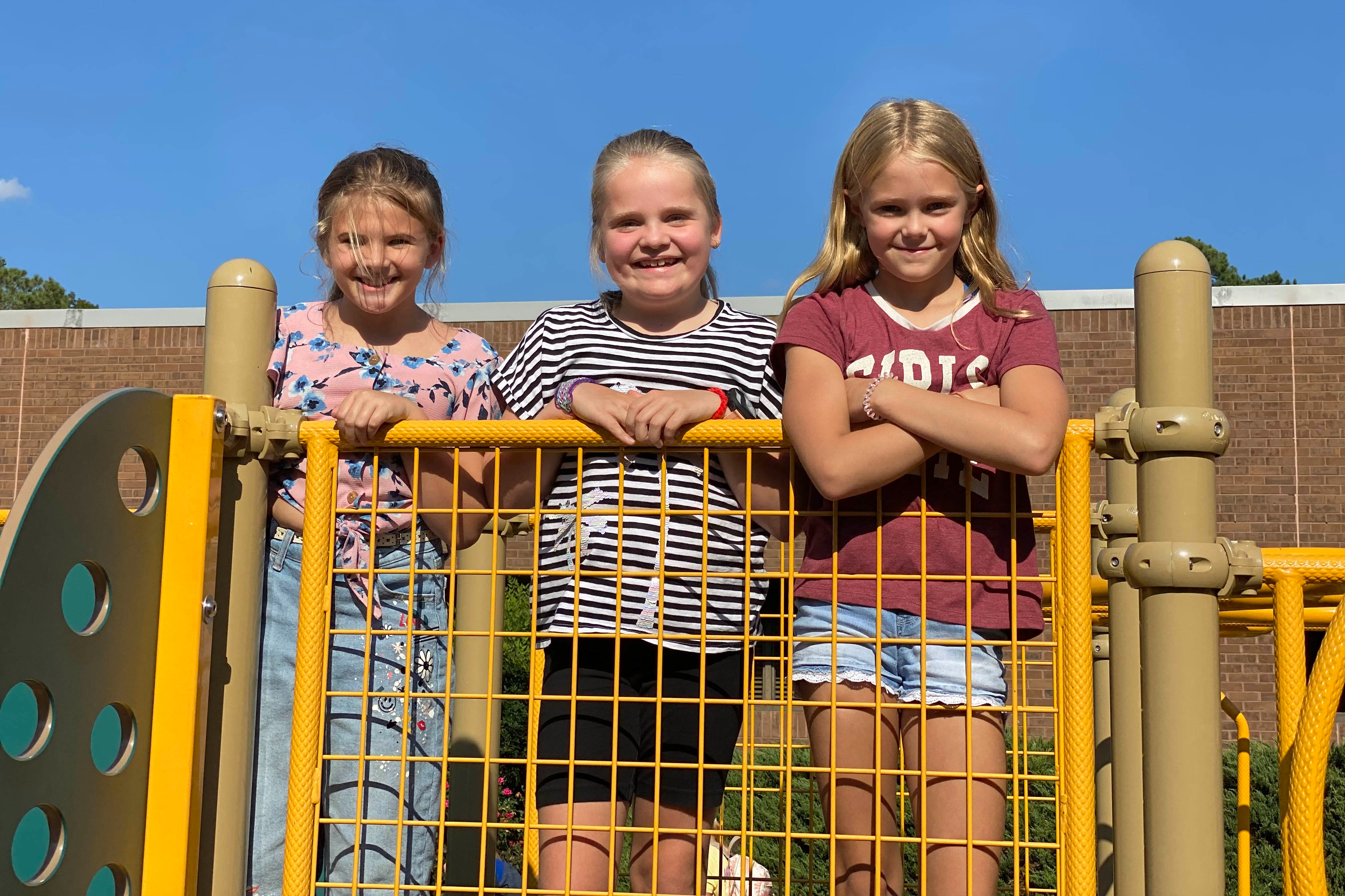 Three girls standing on top of the playground
