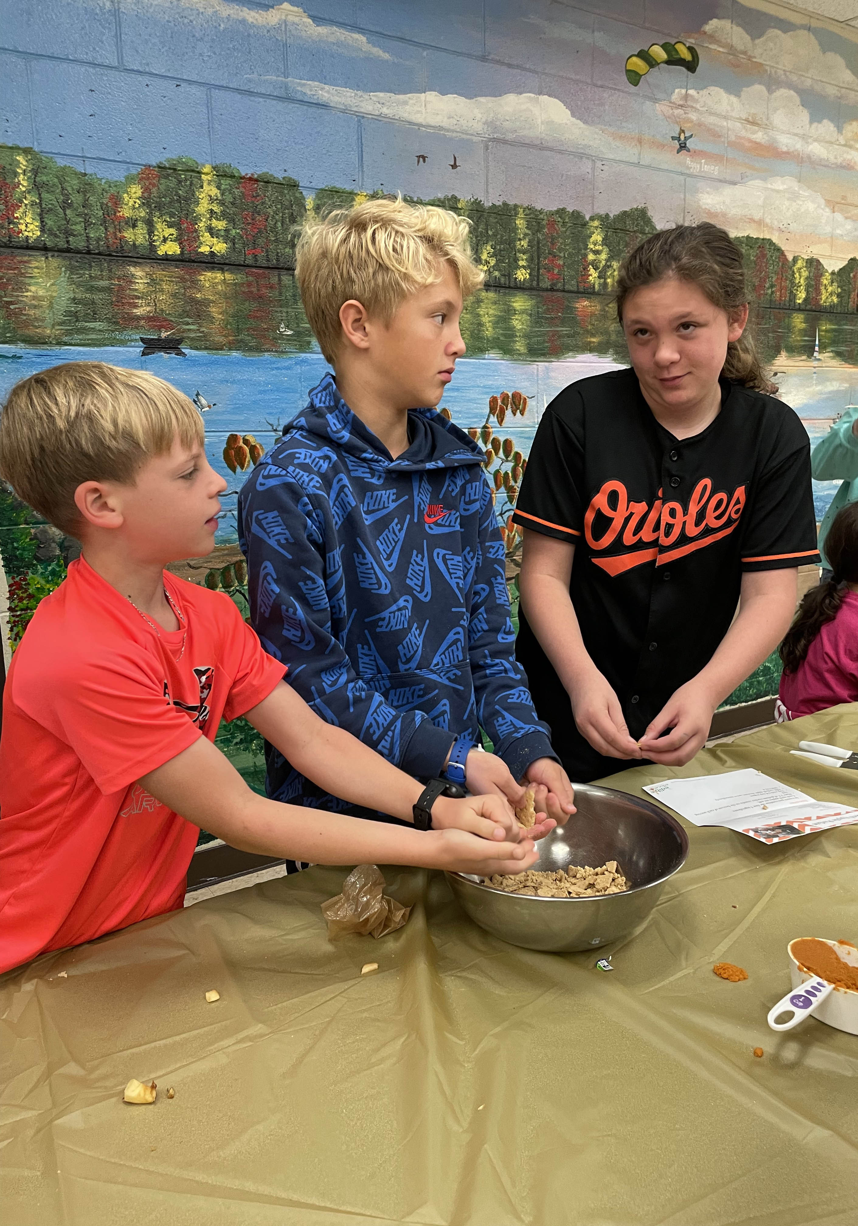 Three students crumbling graham crackers