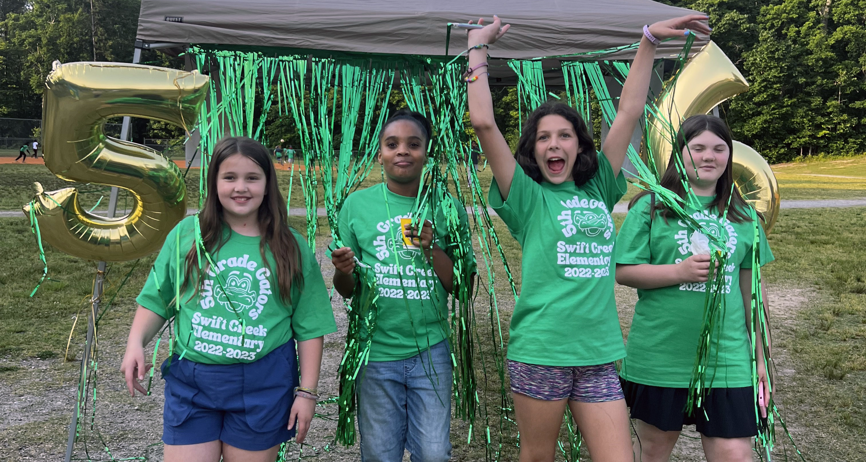Four fifth graders wearing green shirts celebrating