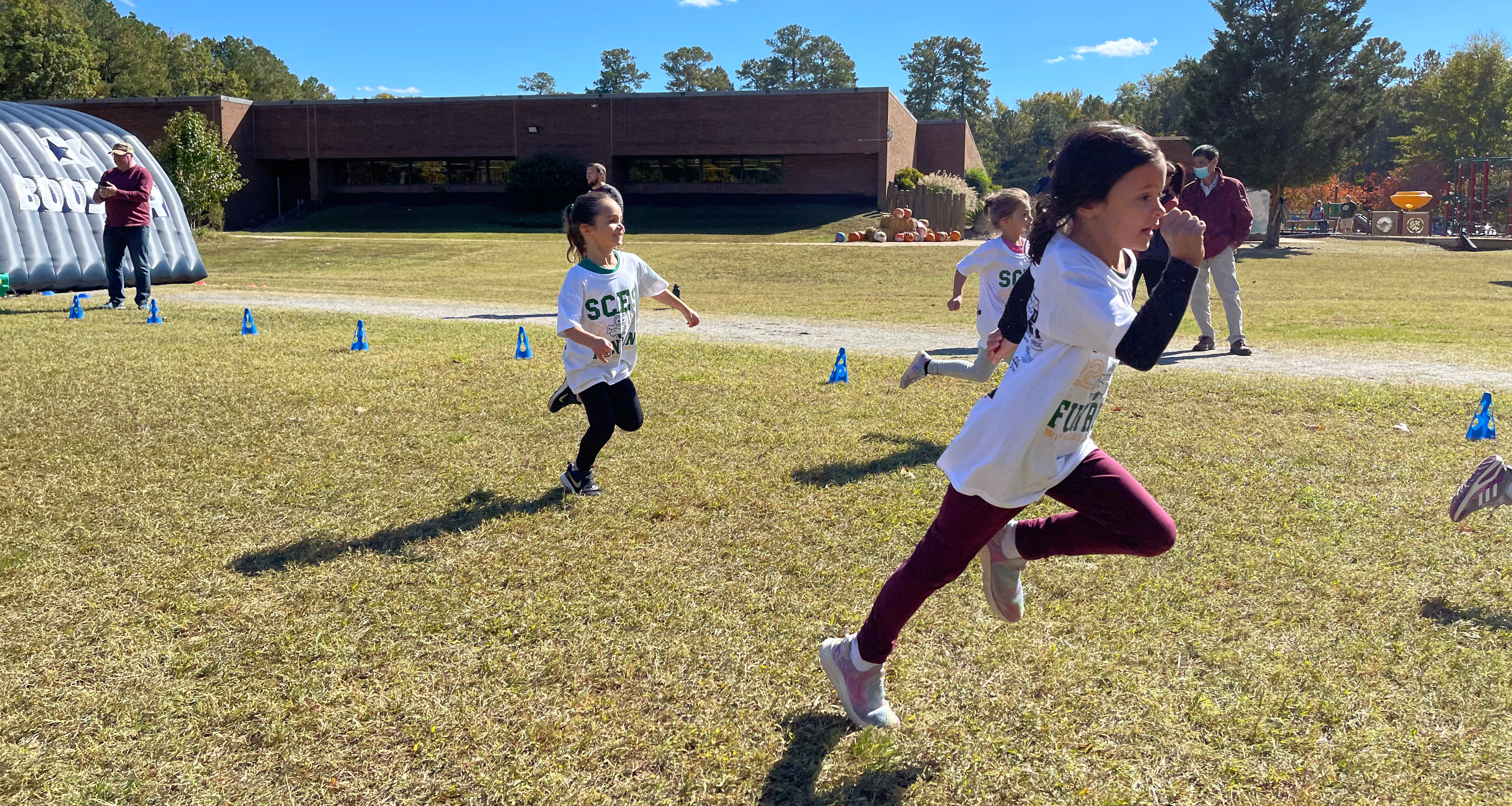 Three students racing outside on the field
