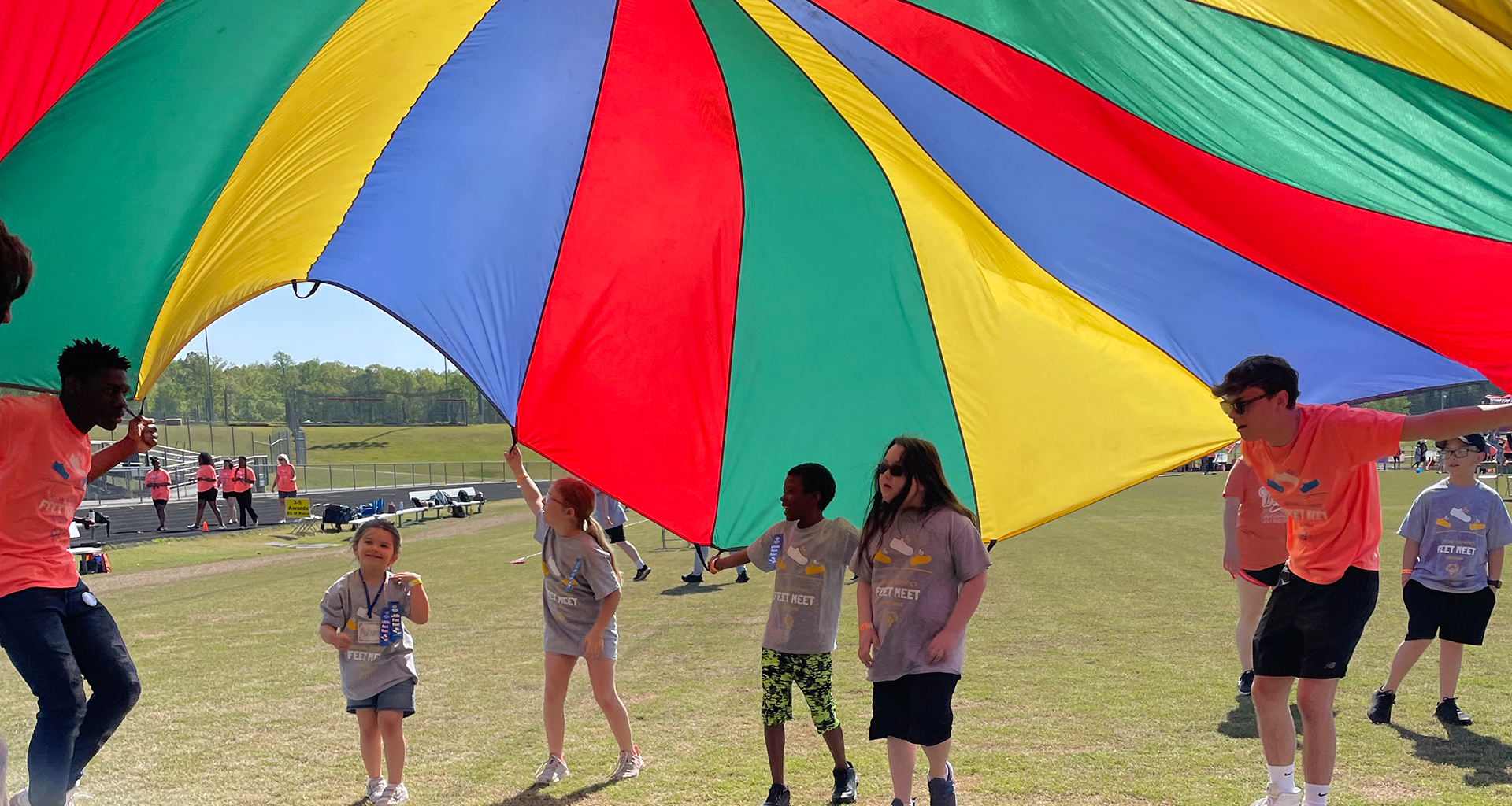 Students waving giant parachute and running under it. 