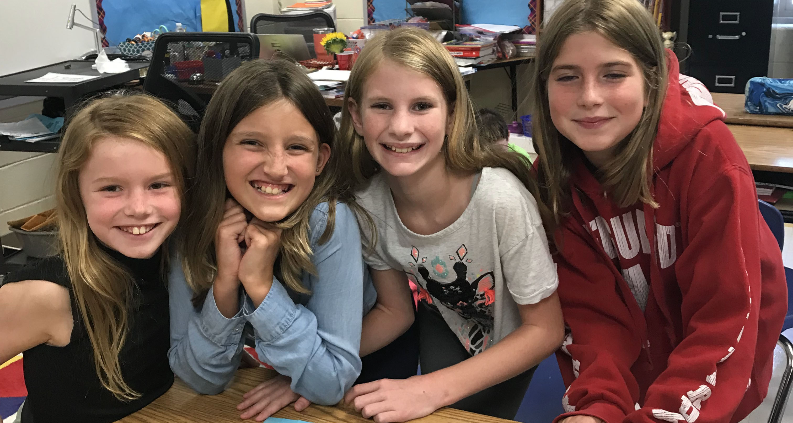 Four girls pose for a photo together in class