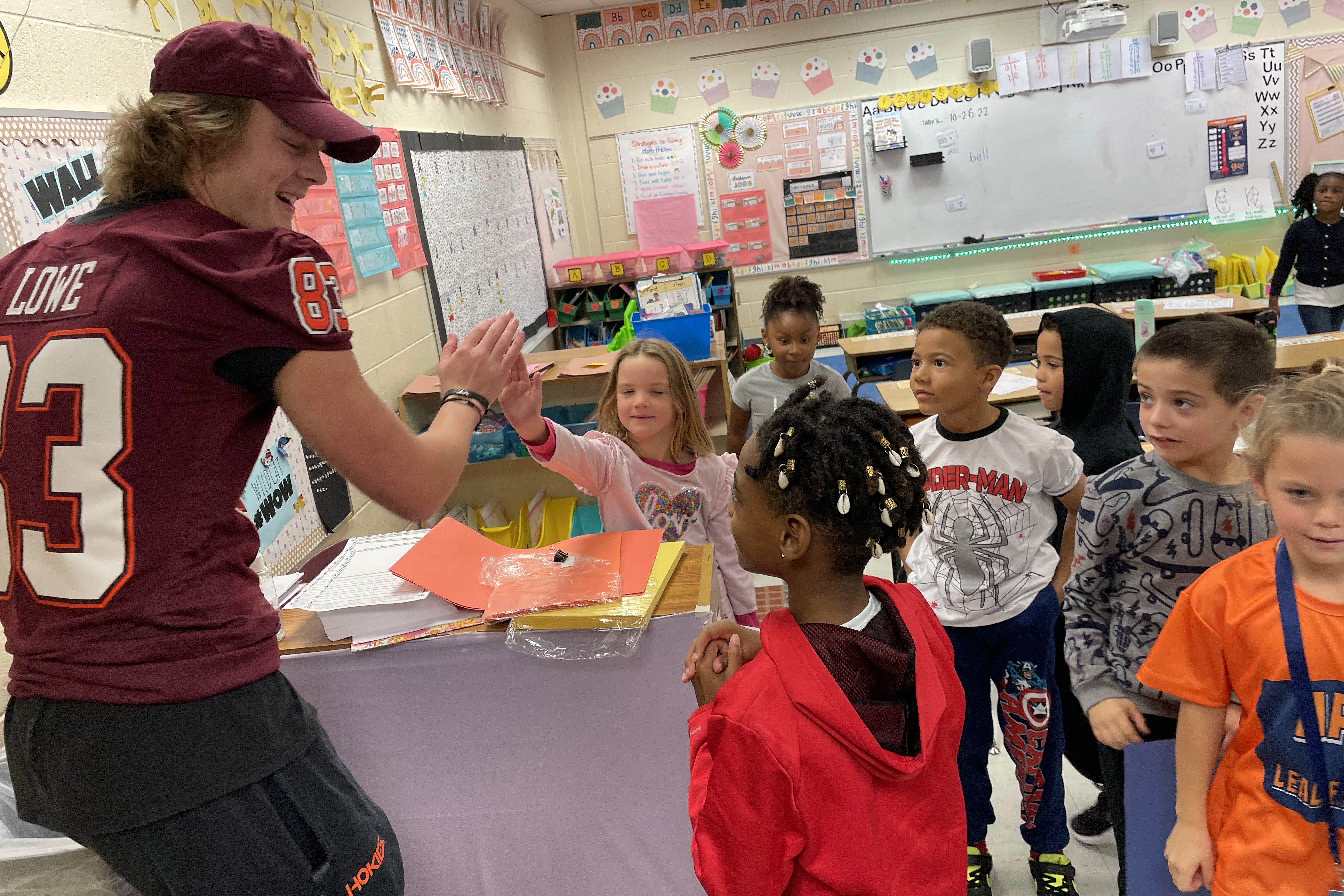 A volunteer giving high fives to students in class