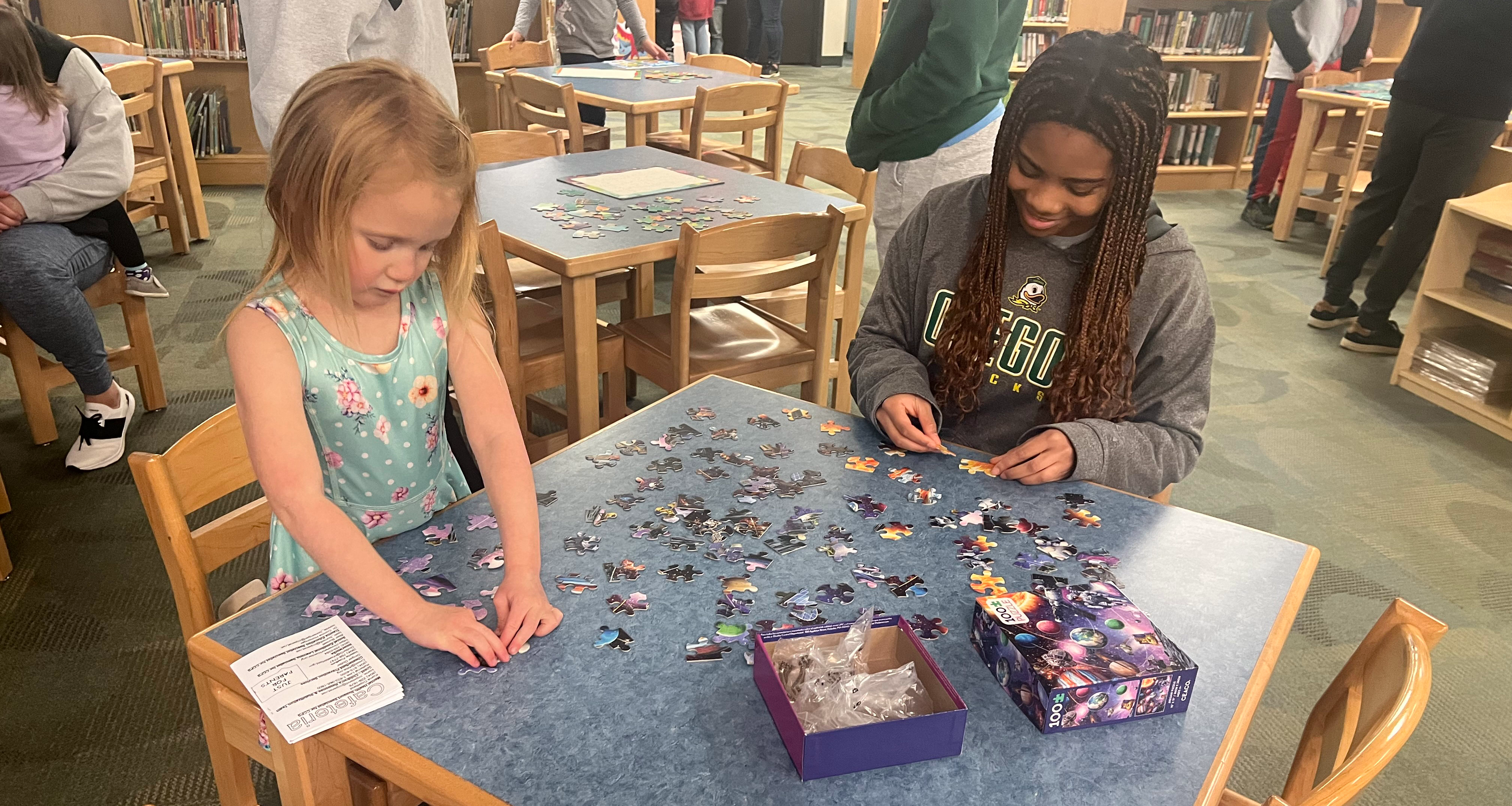 Two students working on a puzzle in the library