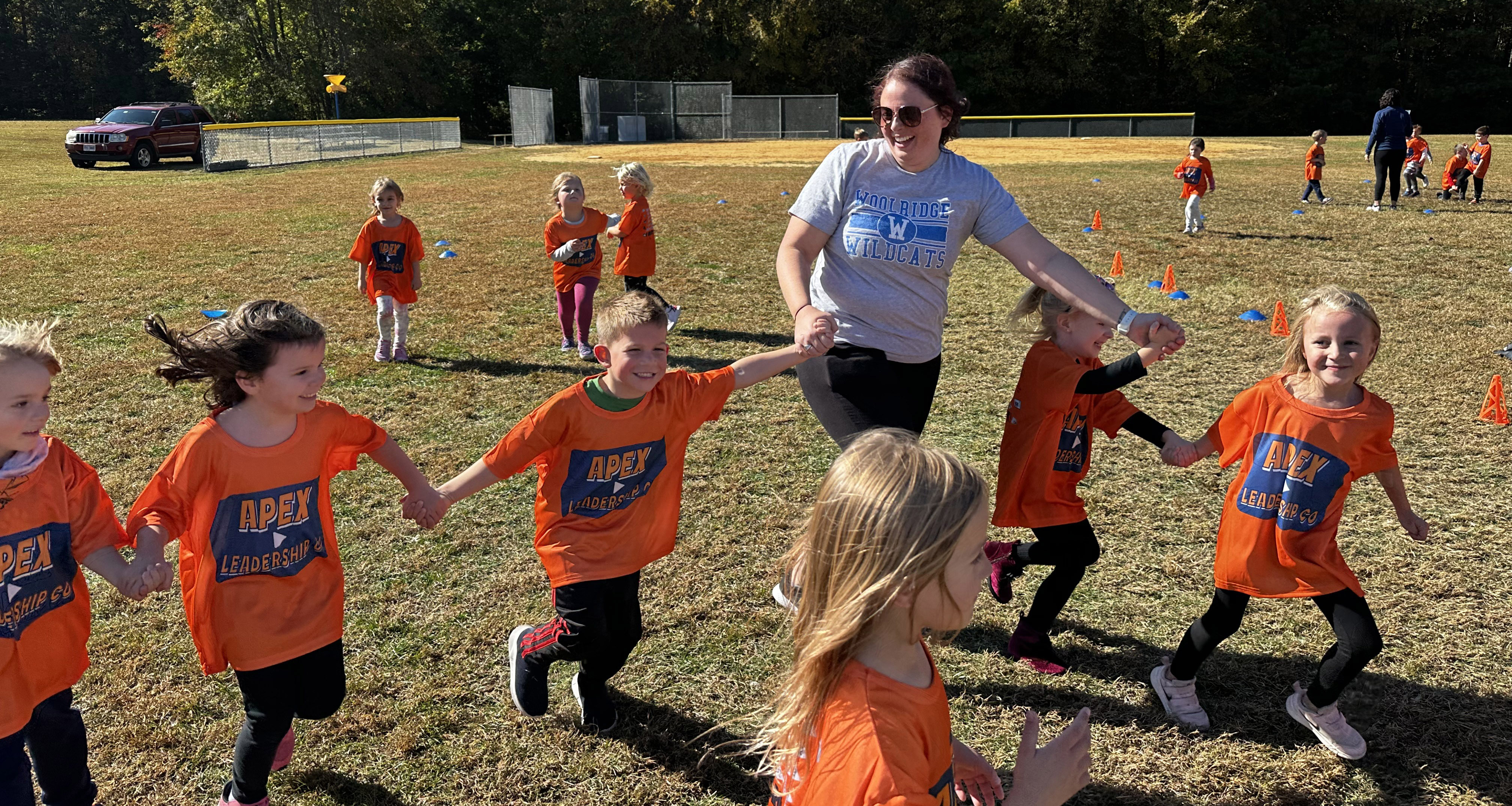 A teacher holding hand with students and running outside