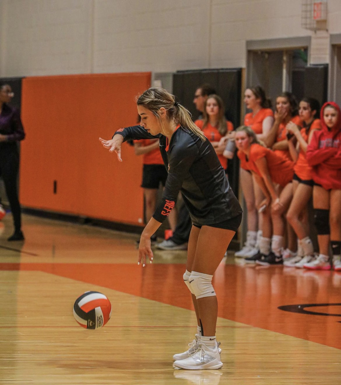 A female volleyball player is getting ready to serve the ball