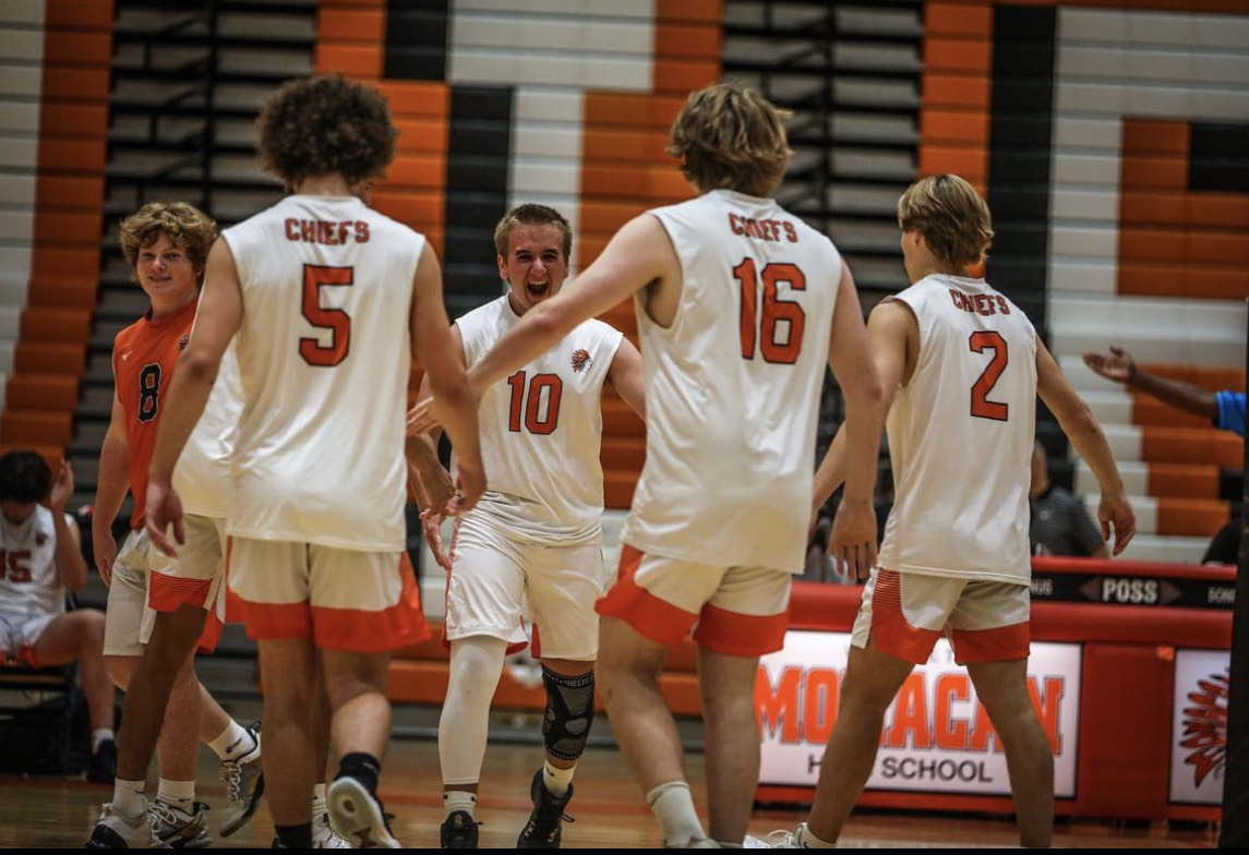 Boys volleyball players celebrating together after a play