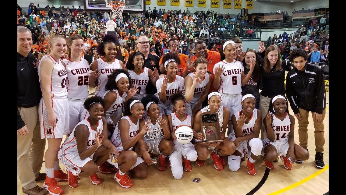 The girls basketball team poses with a trophy after a win