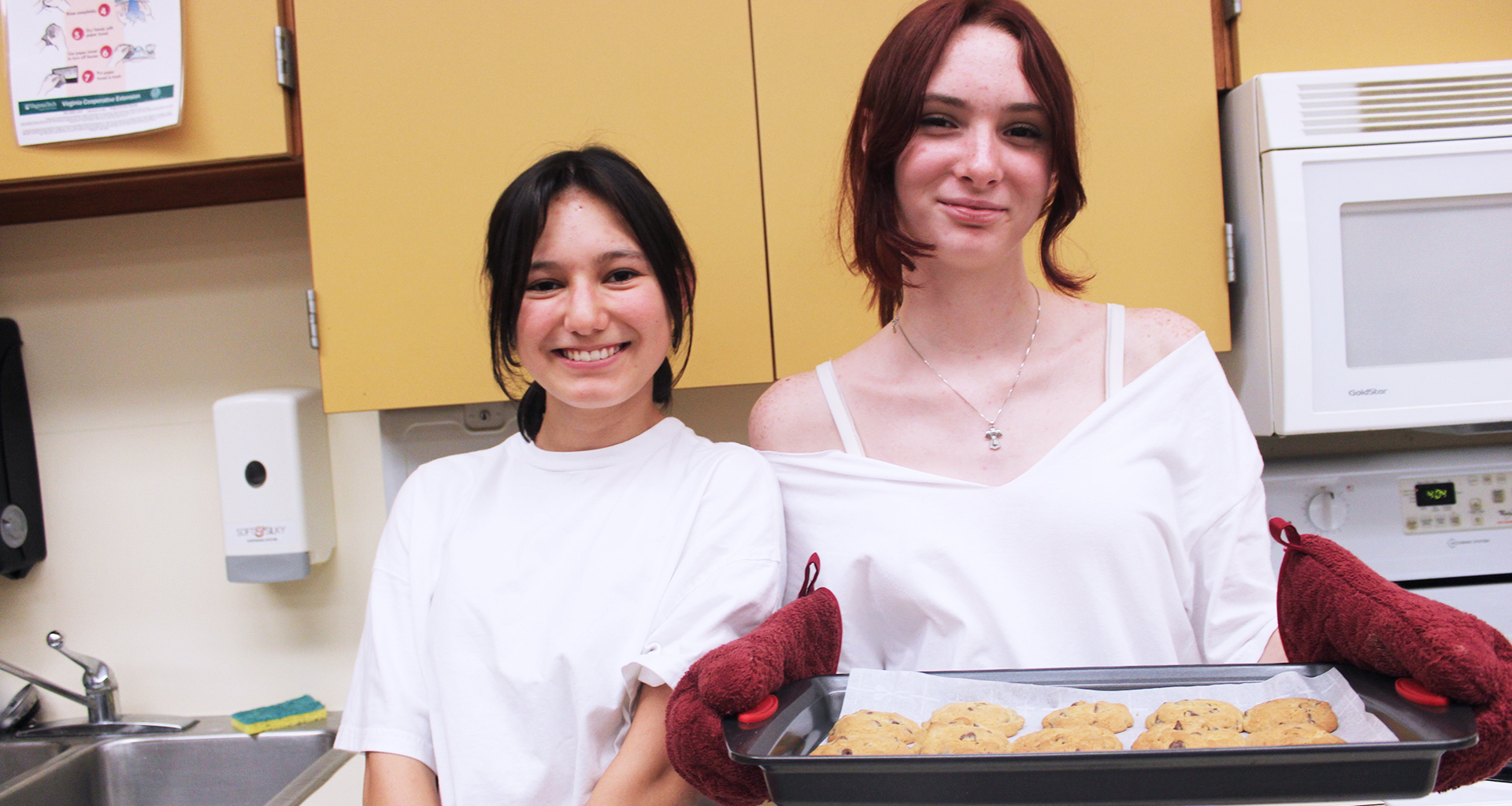 Two students serving cookies