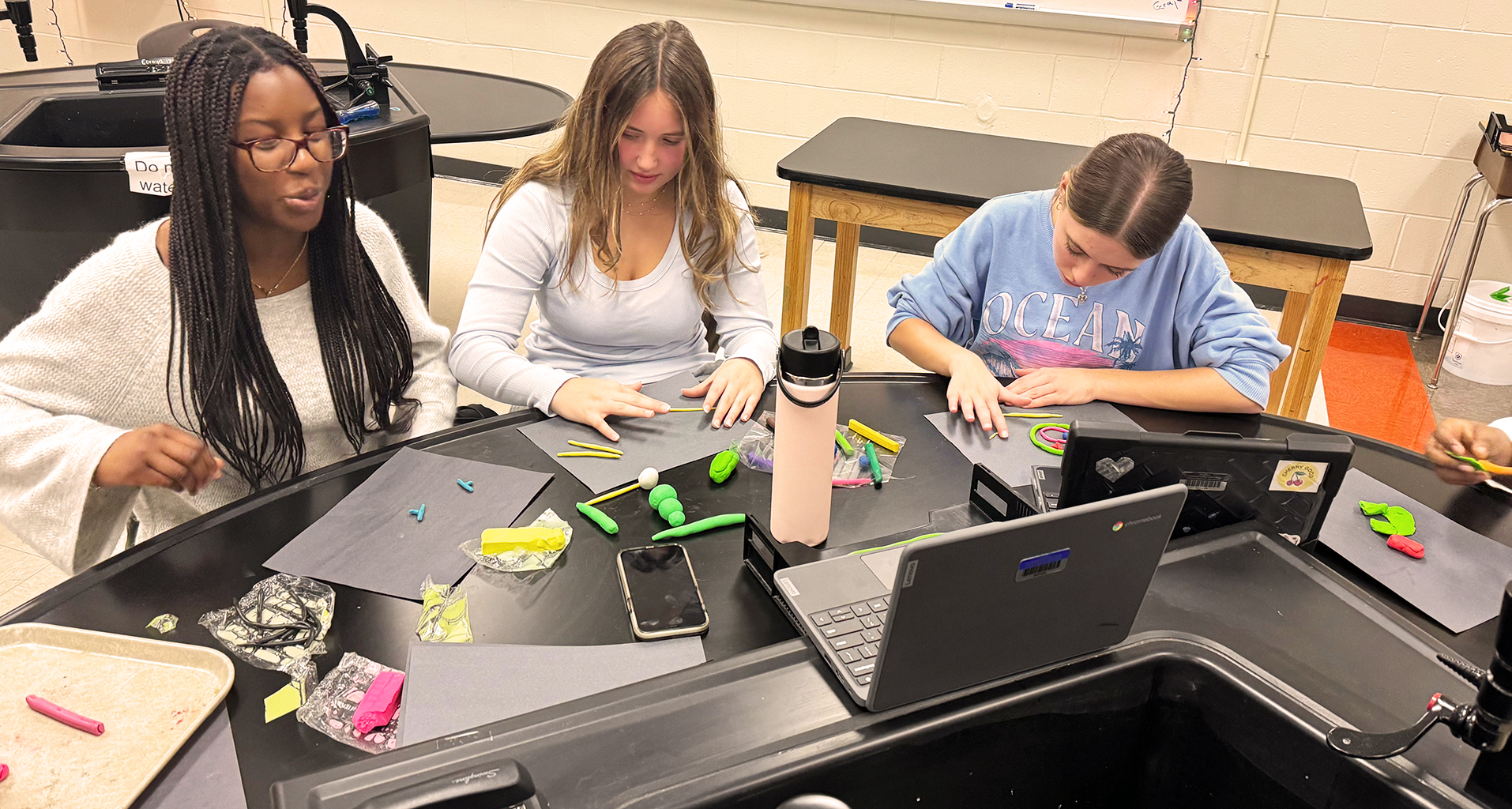 Three students working together on a project in classroom