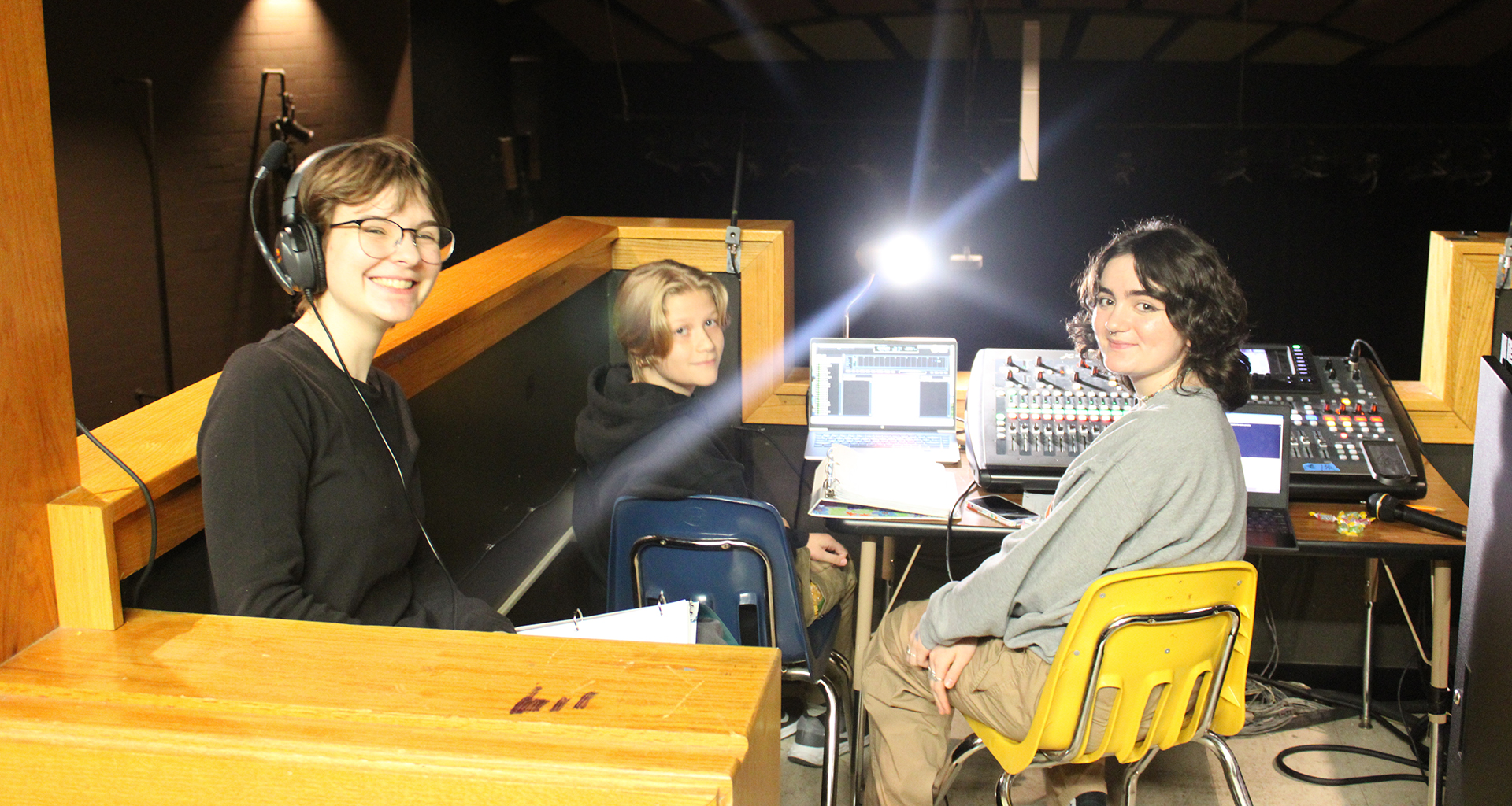 Three students in sound box smile for camera.