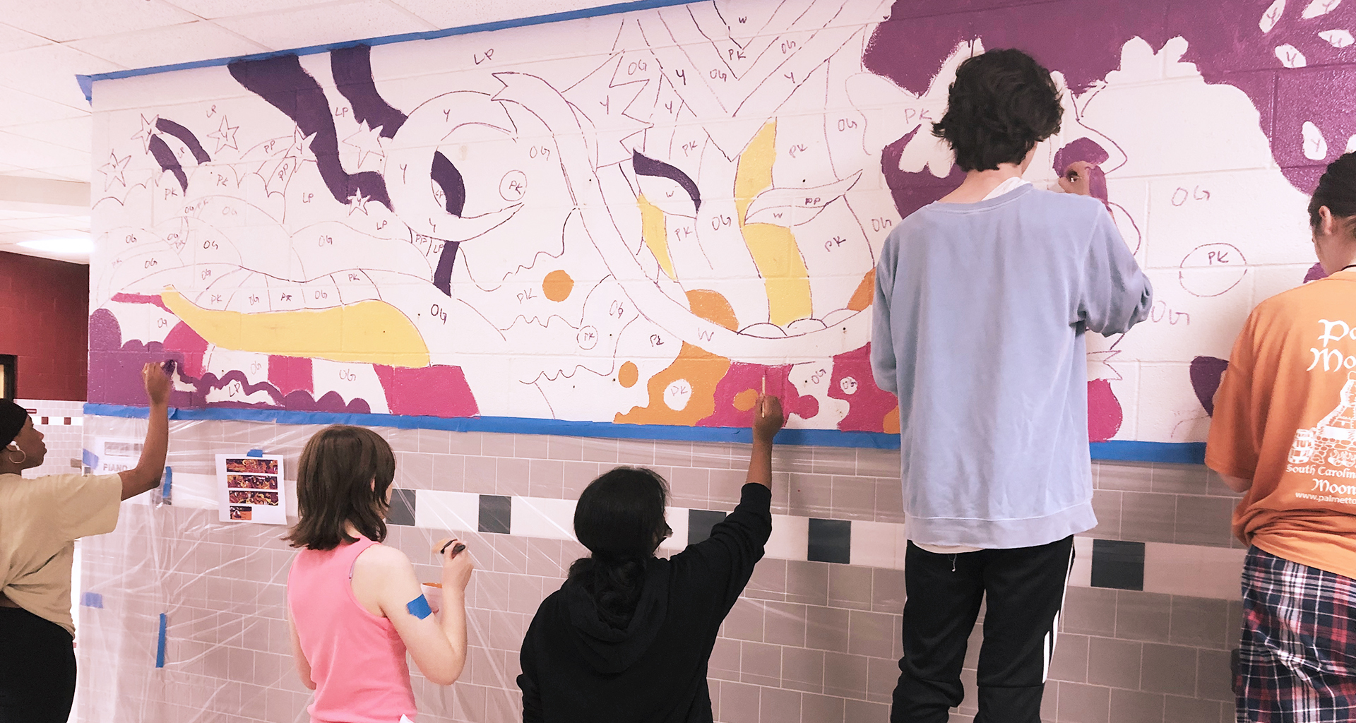 Several students working on a hallway mural.