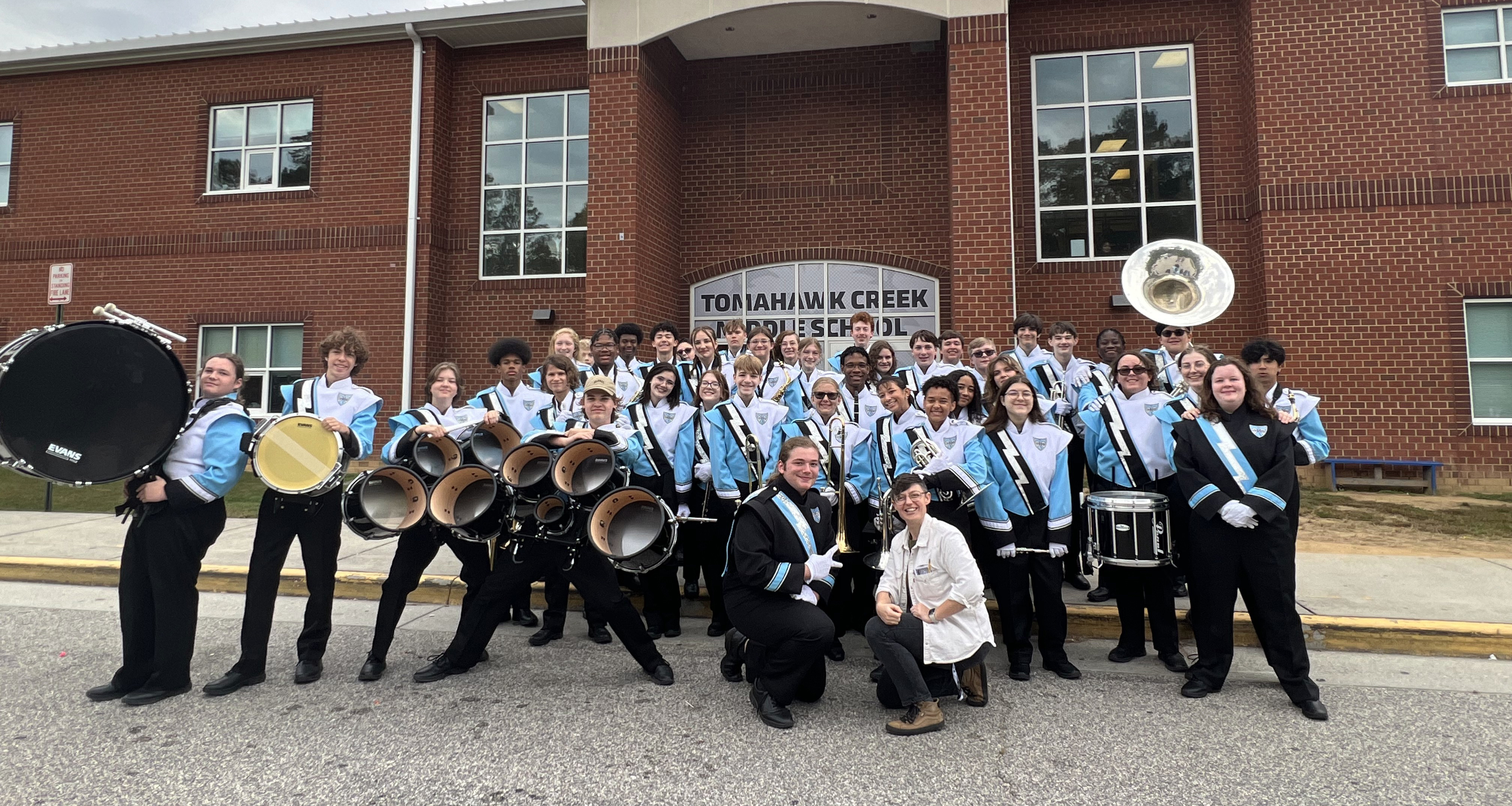 Marching band poses in front of the school building for a photo
