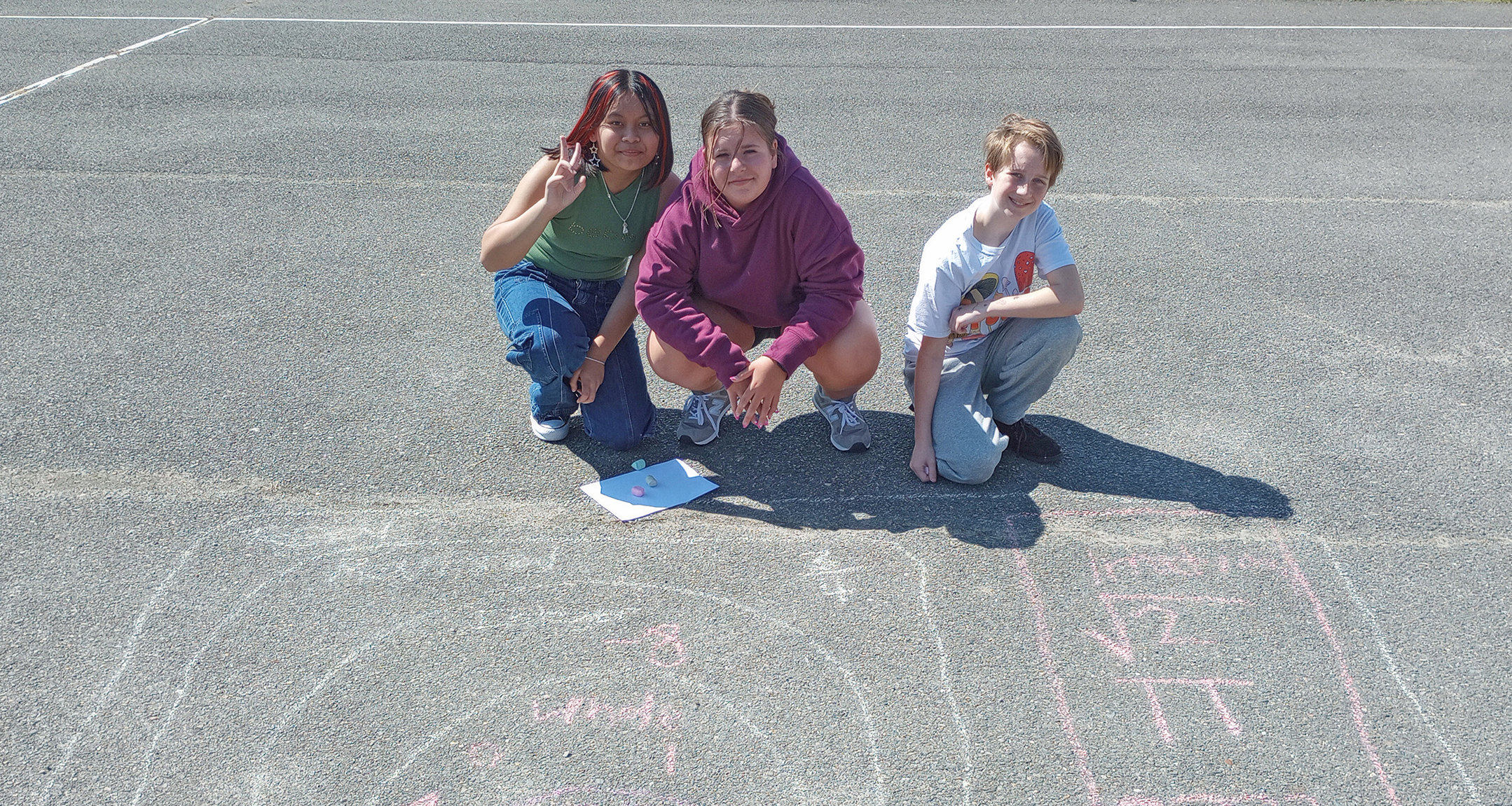 Three students solving math problems with chalk on the black top
