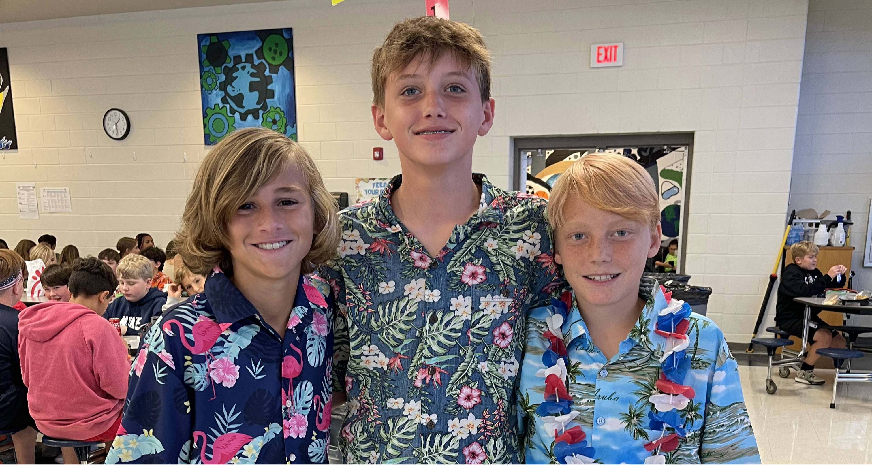 Three boys wearing floral shirts pose for a photo together