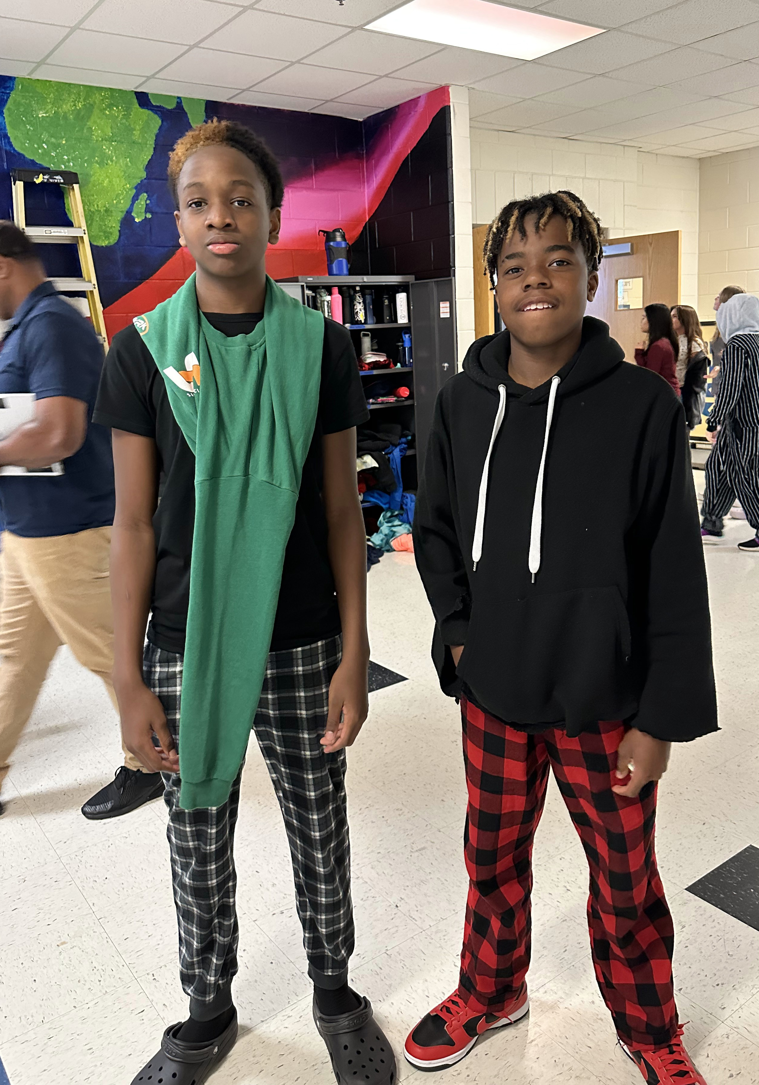 Two students pose for a photo in the hallway