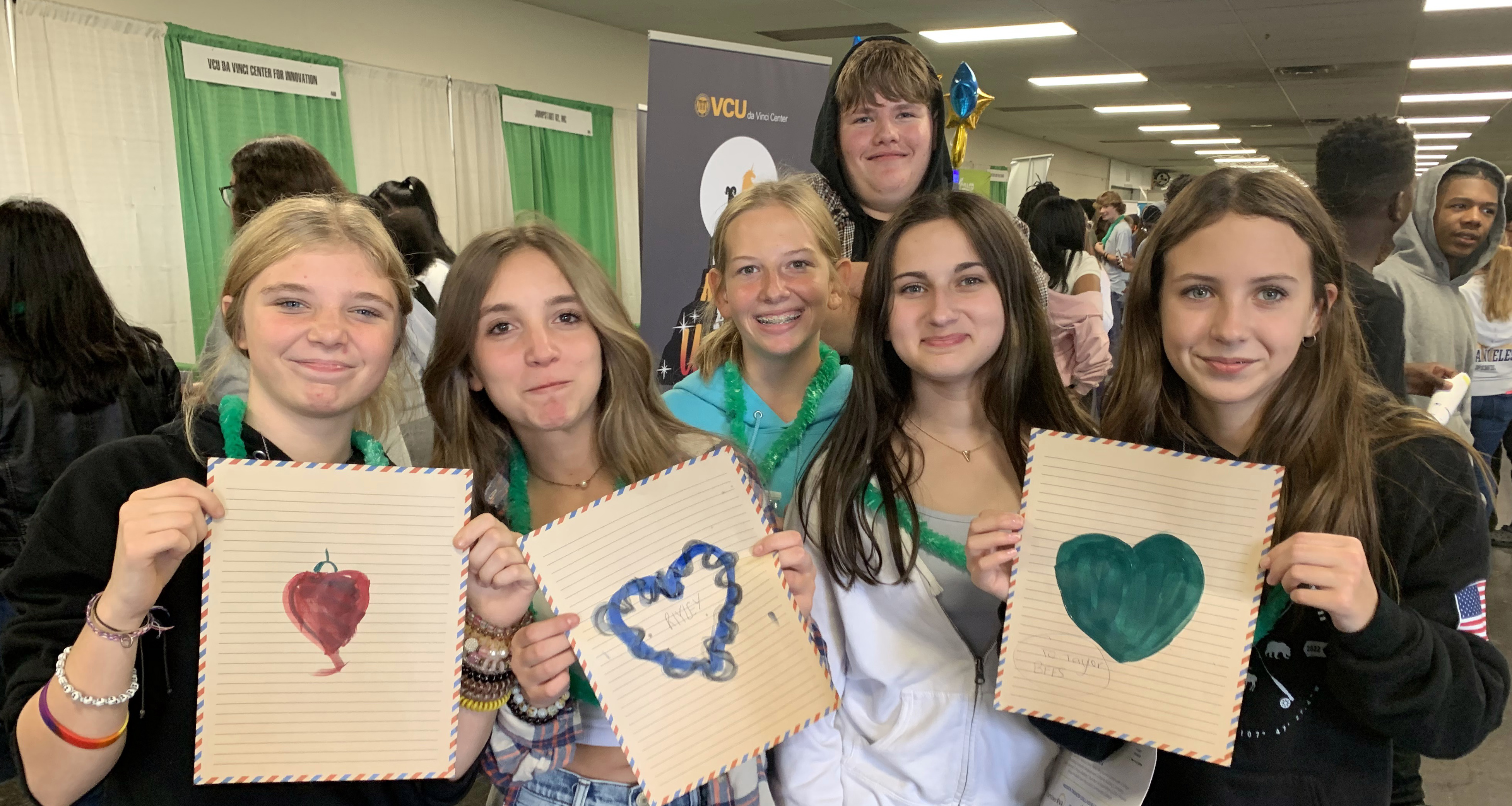 A group of students holding pieces of paper with a heart on them