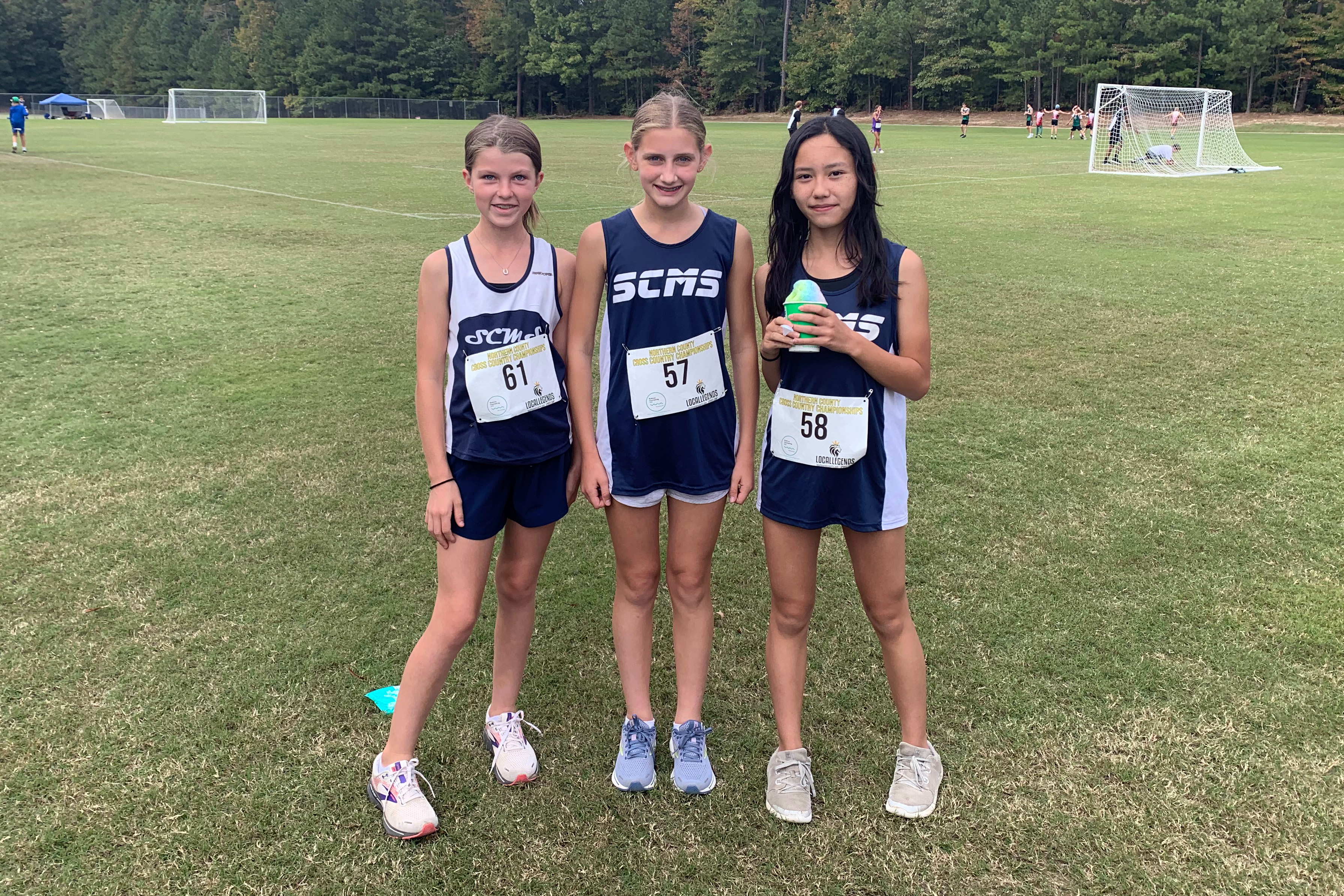 Three girls cross country runners pose for a photo