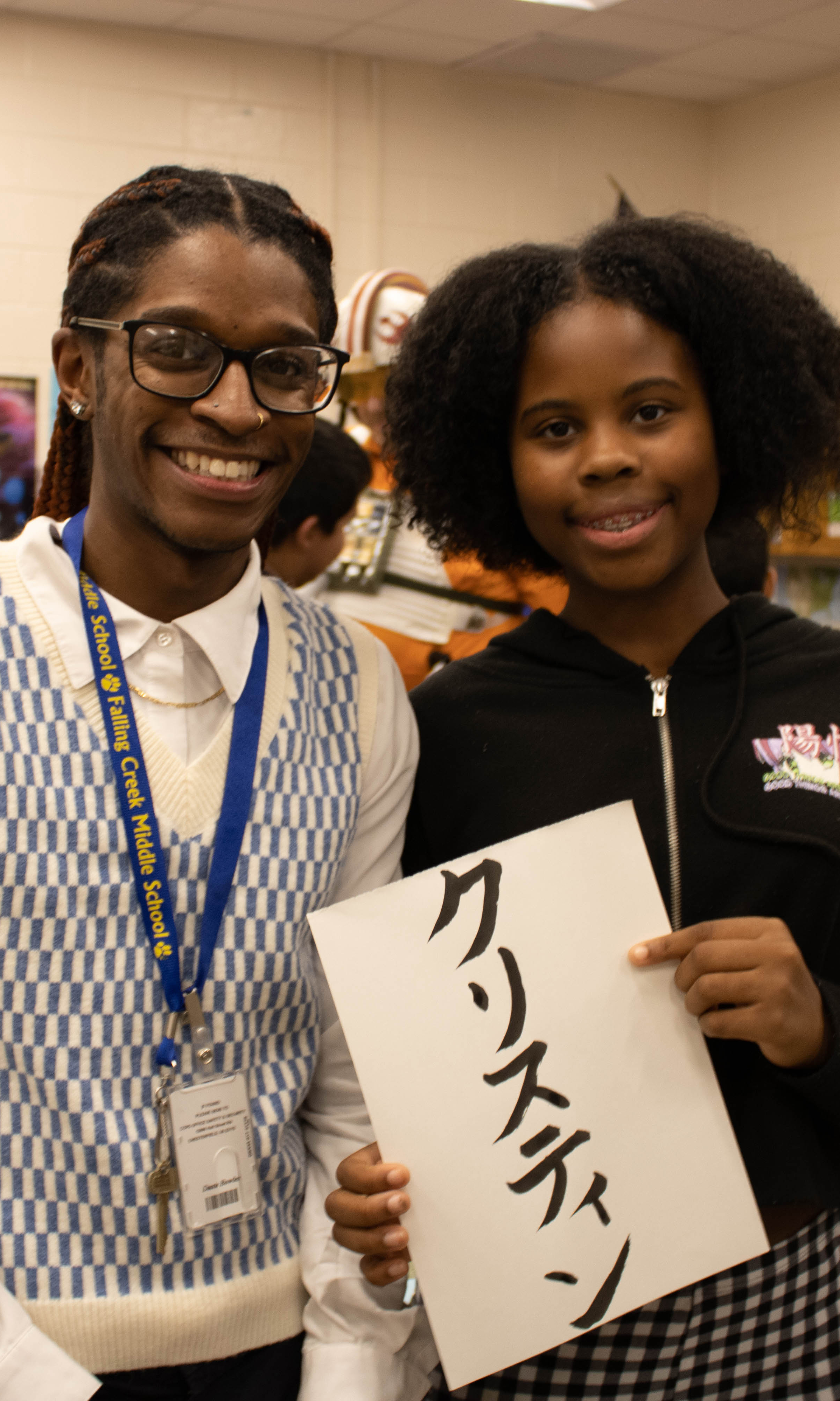 A teacher and a student holding a piece of paper pose for a photo