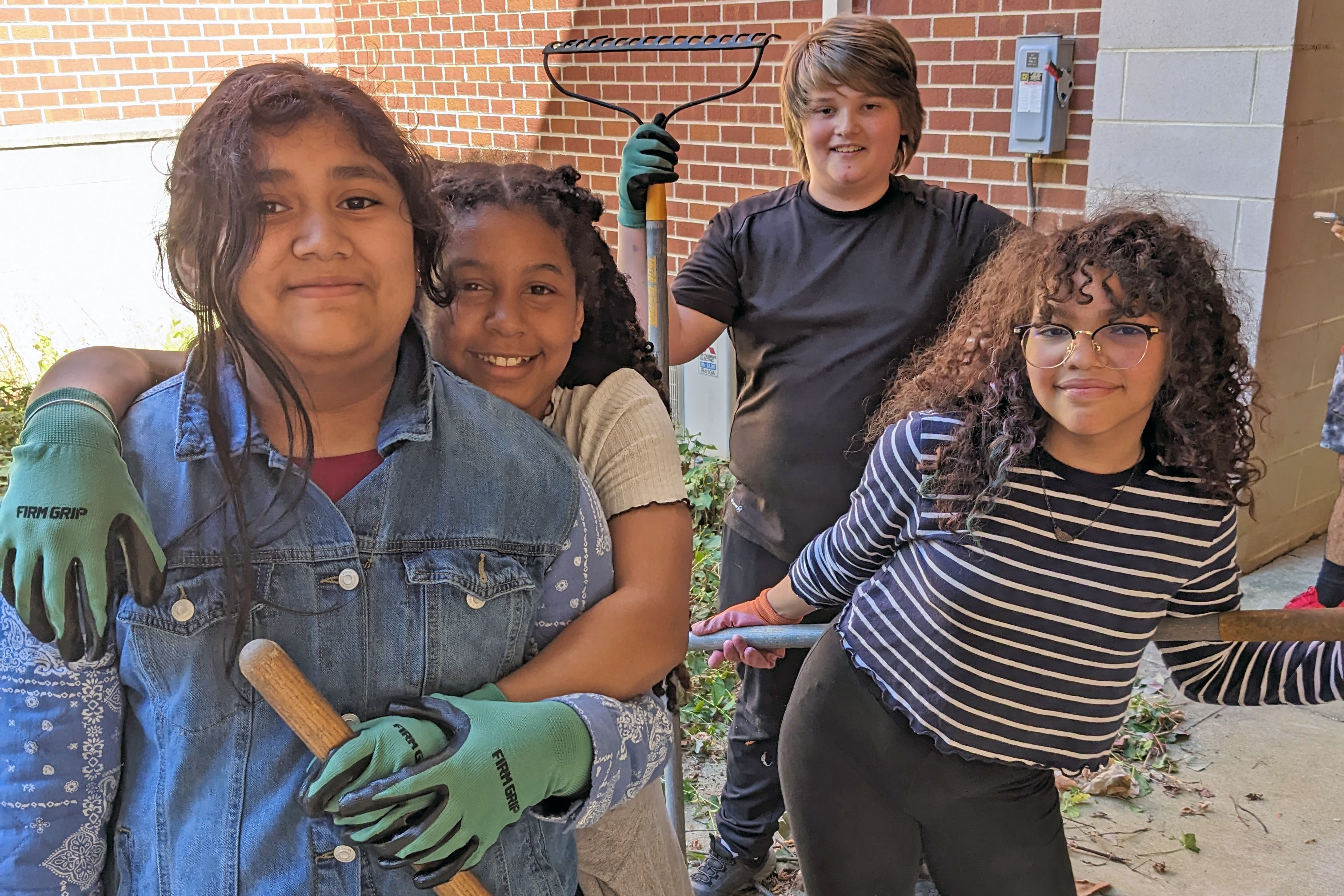Four students volunteering outside pose for a photo