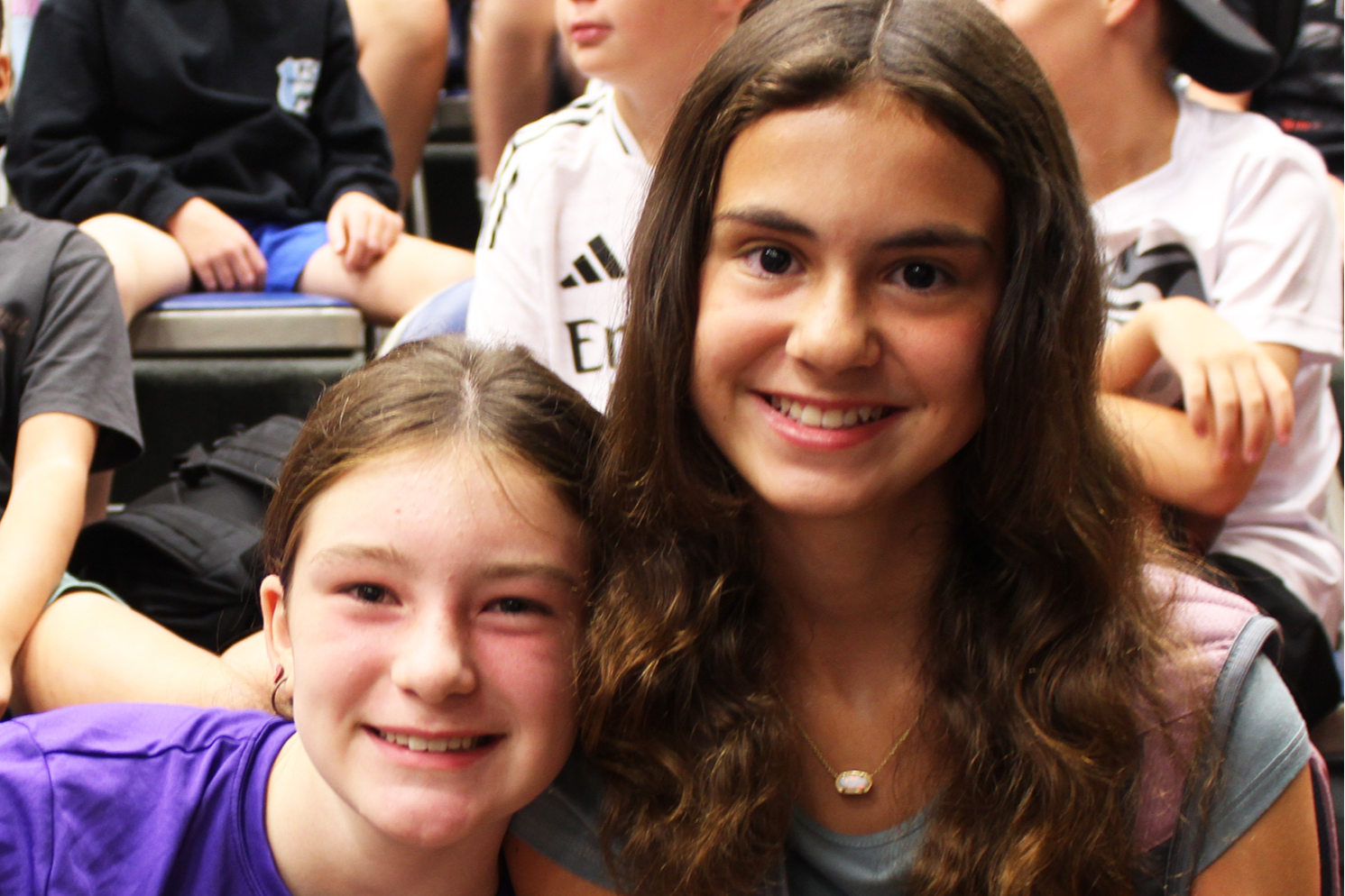 Two girls pose for a photo together in the hallway