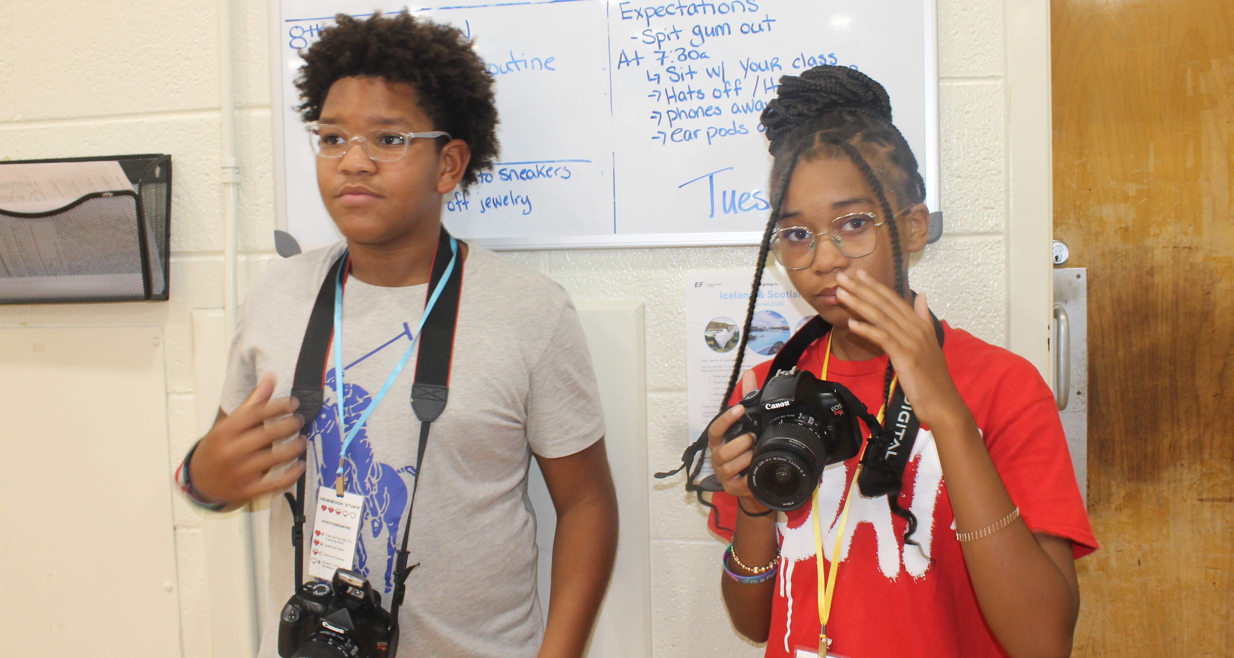 Two students with cameras getting ready to take pictures in class