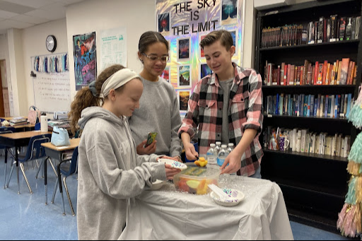 Three students getting fruit from a tray