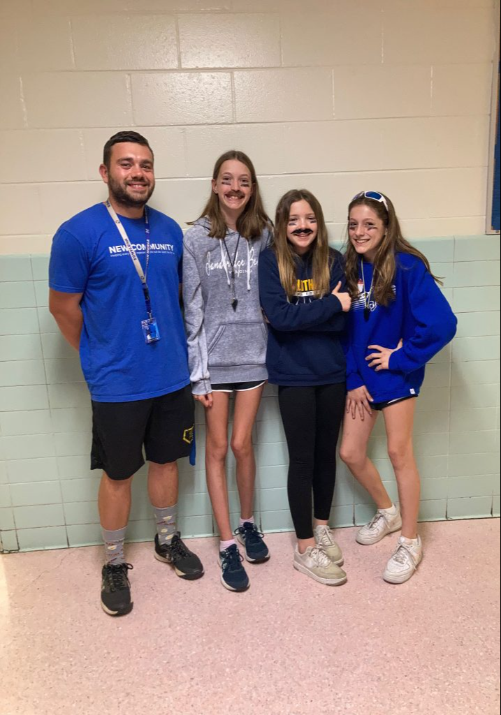 A teacher takes a photo with three students