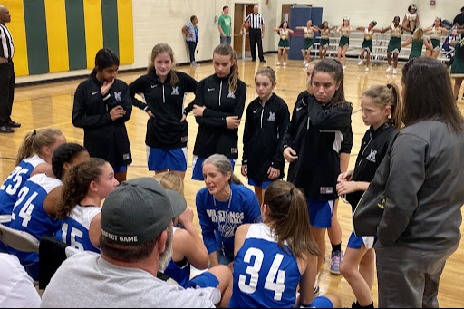 The girls basketball team huddled up with their coach