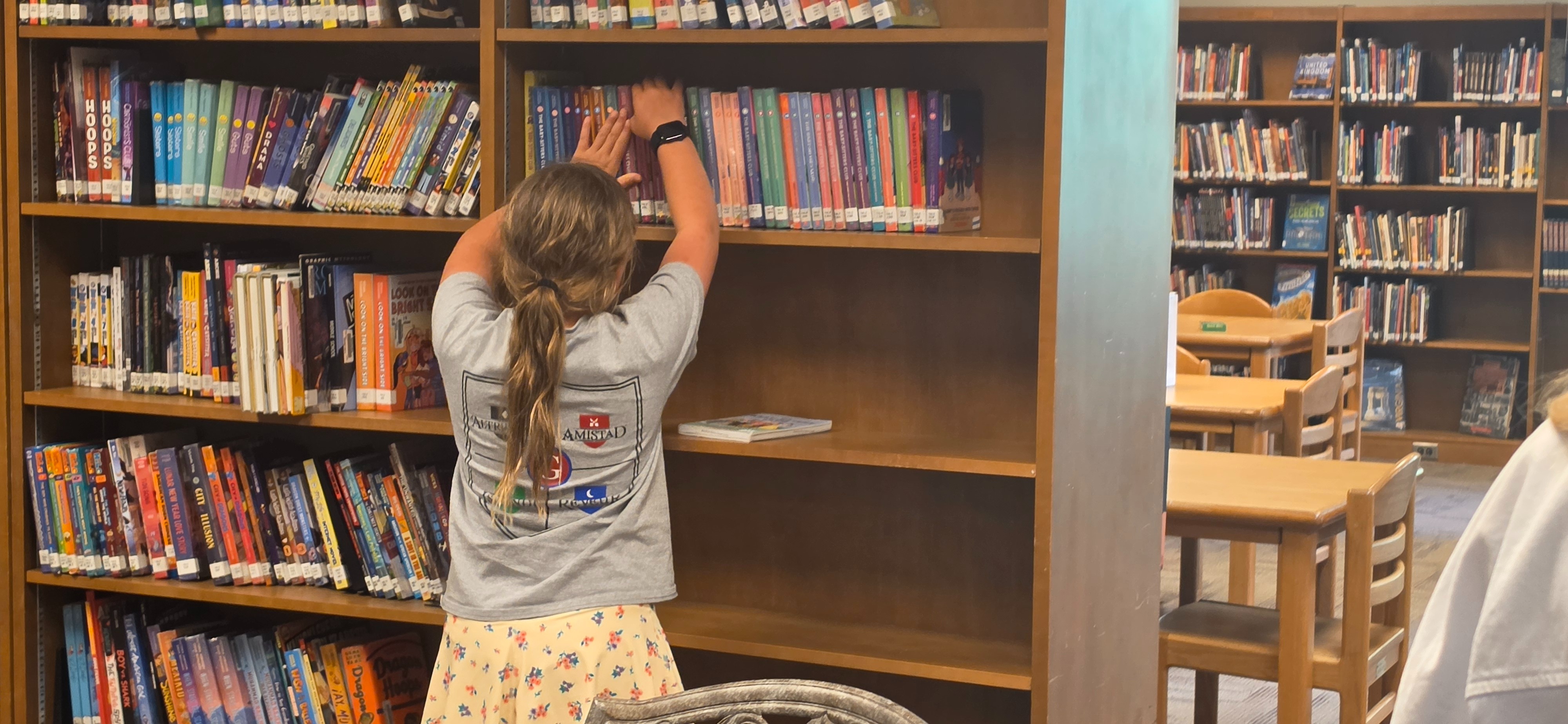 A student pullig a book of library shelf