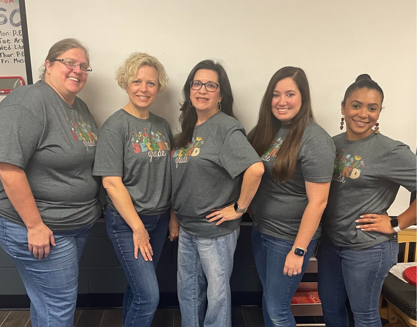 group of ladies in gray shirts standing posing