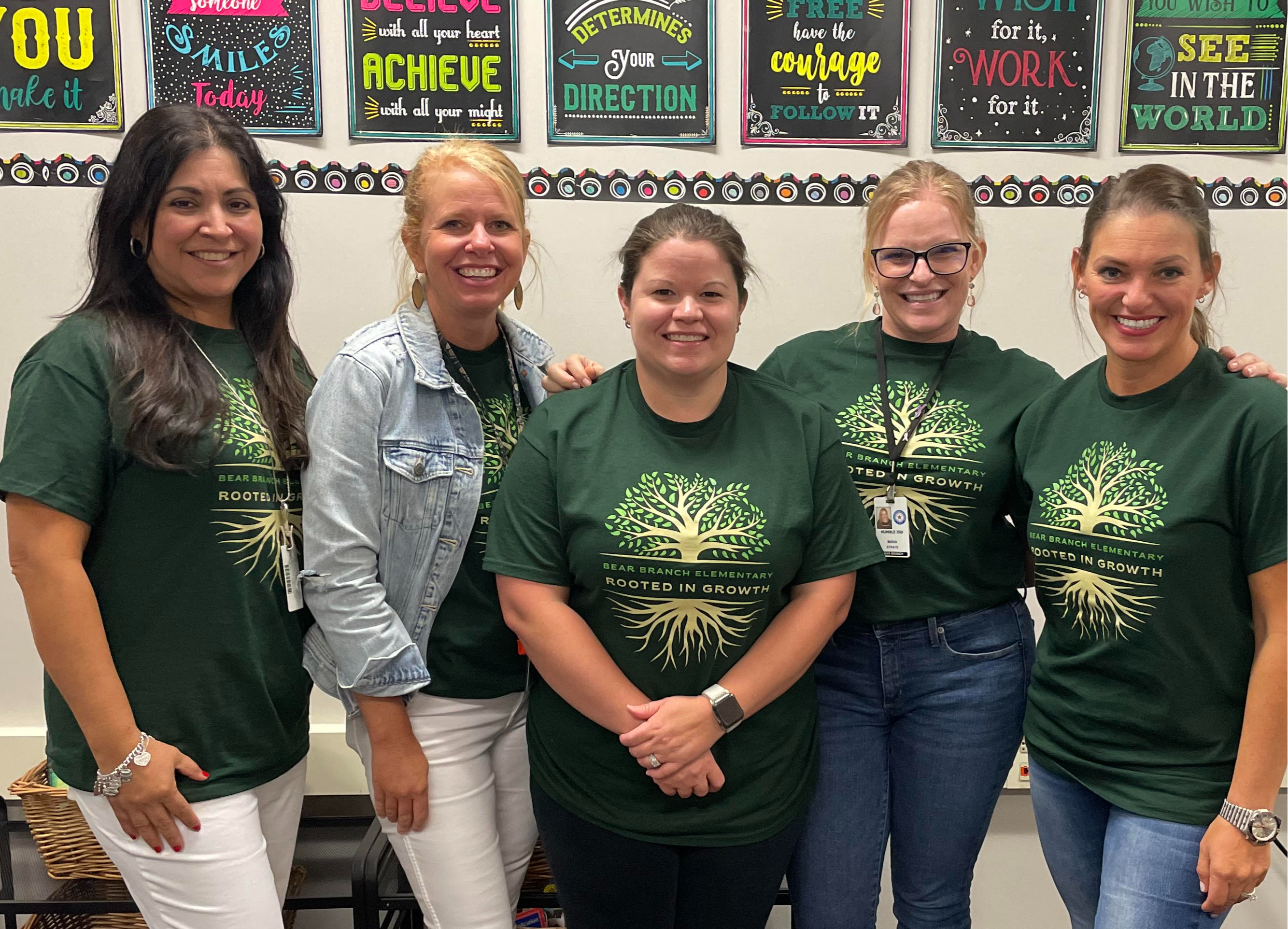 Fourth Grade teachers in green shirts standing posing in school hallway