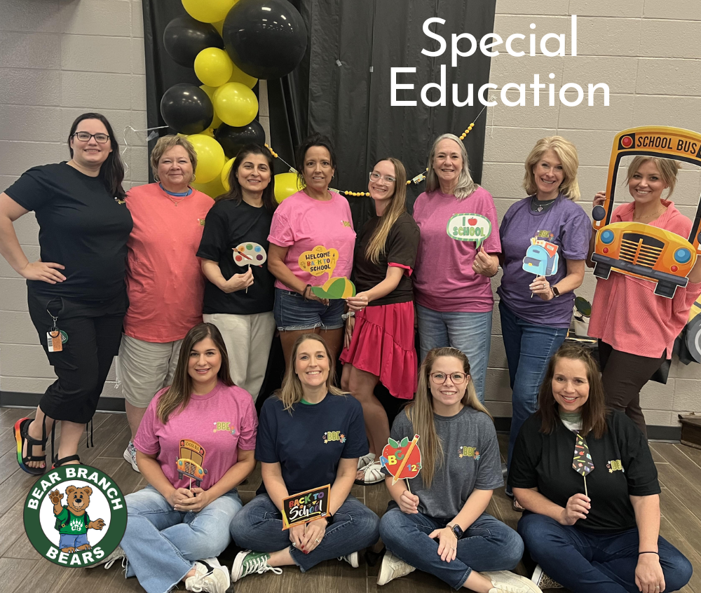 group of teachers in green shirts posing with cartoon bear 