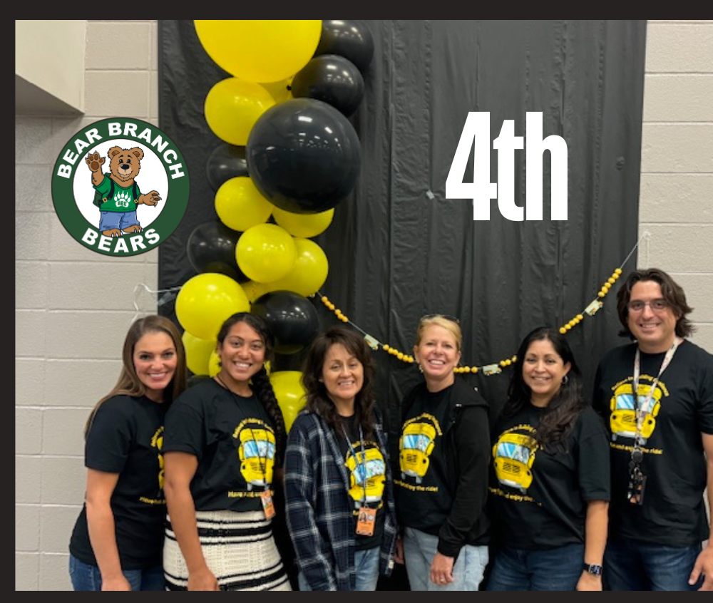 Fourth Grade teachers in green shirts standing posing in school hallway