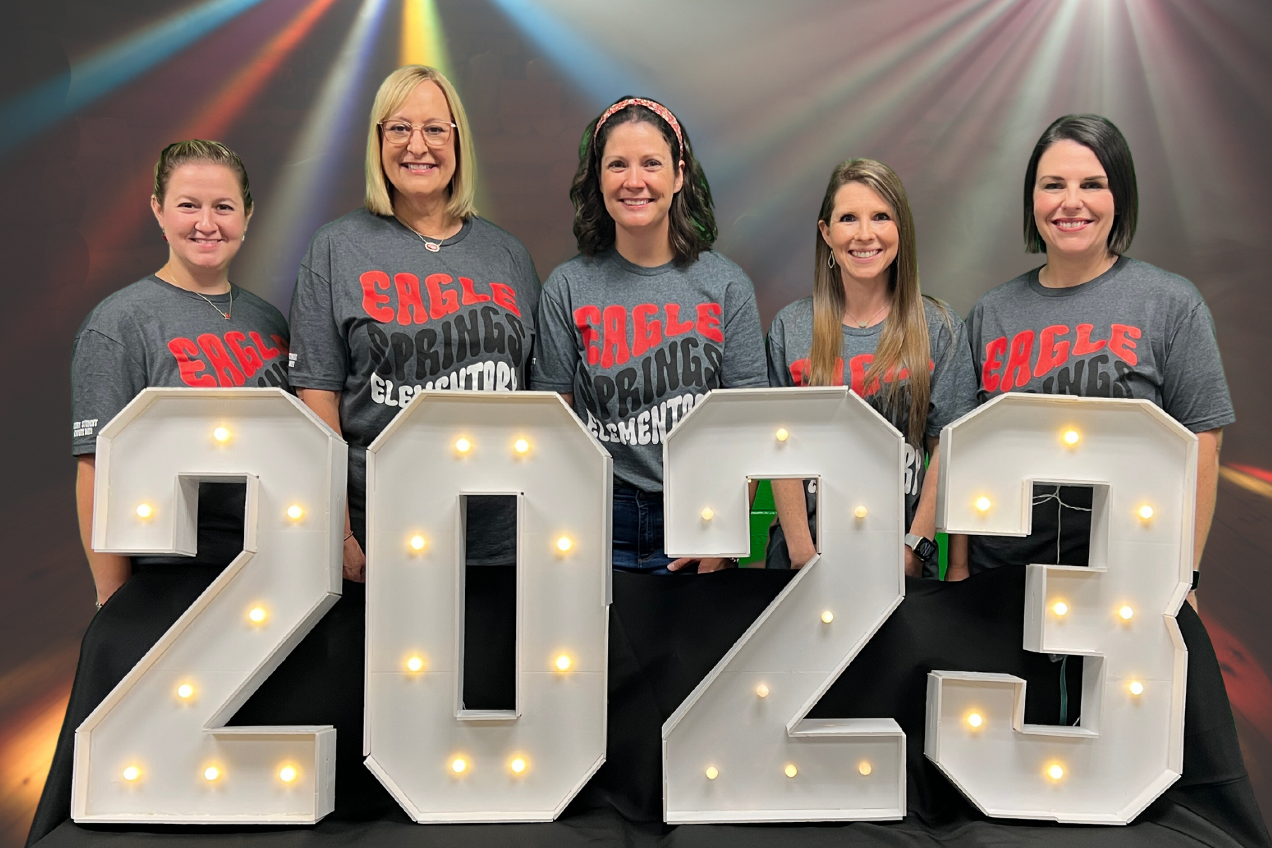 teachers posing behind lighted numbers 2023