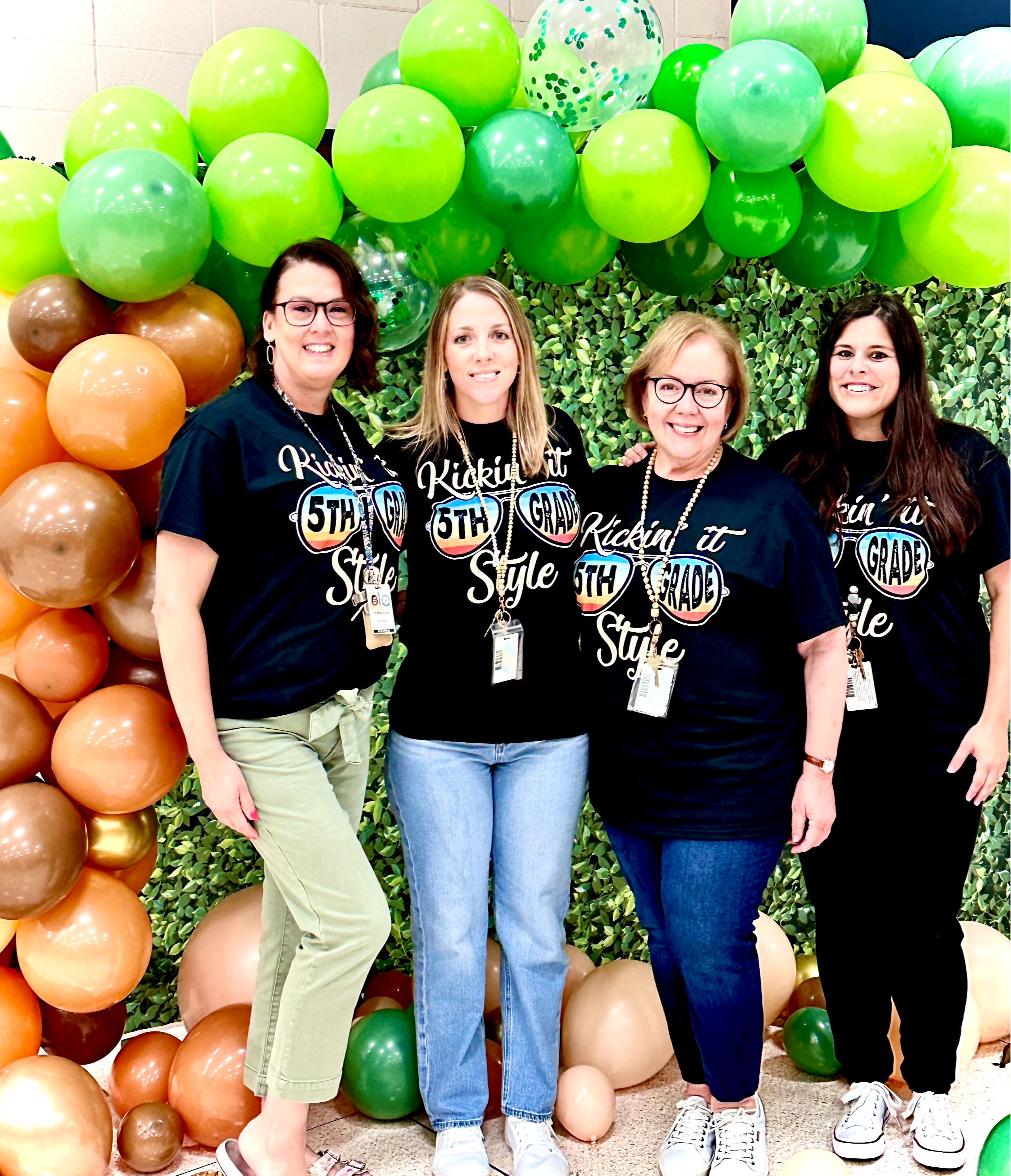 group of teachers in black shirts standing posing with balloons