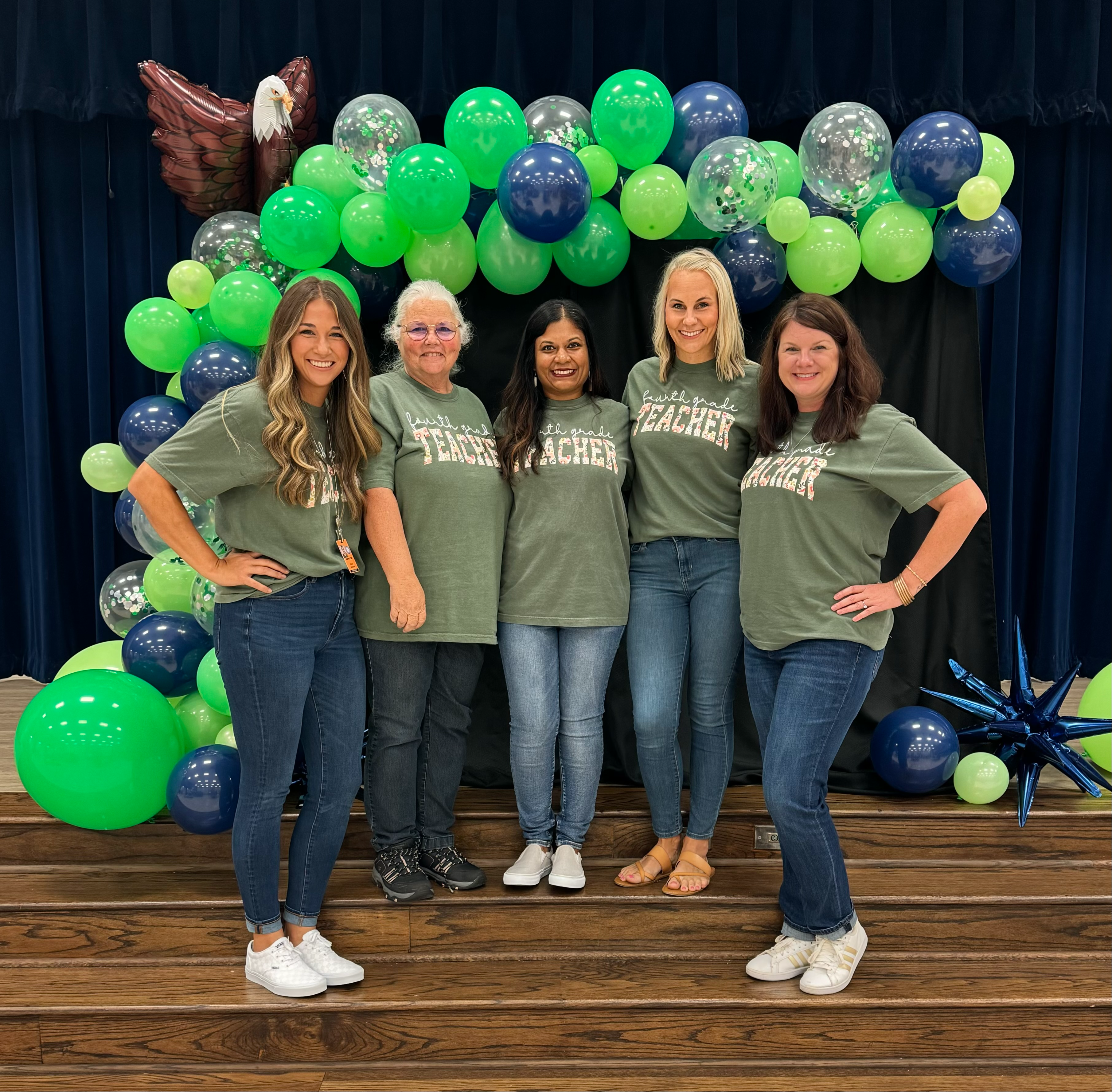 Fourth Grade teachers in  gray shirts standing posing with balloons
