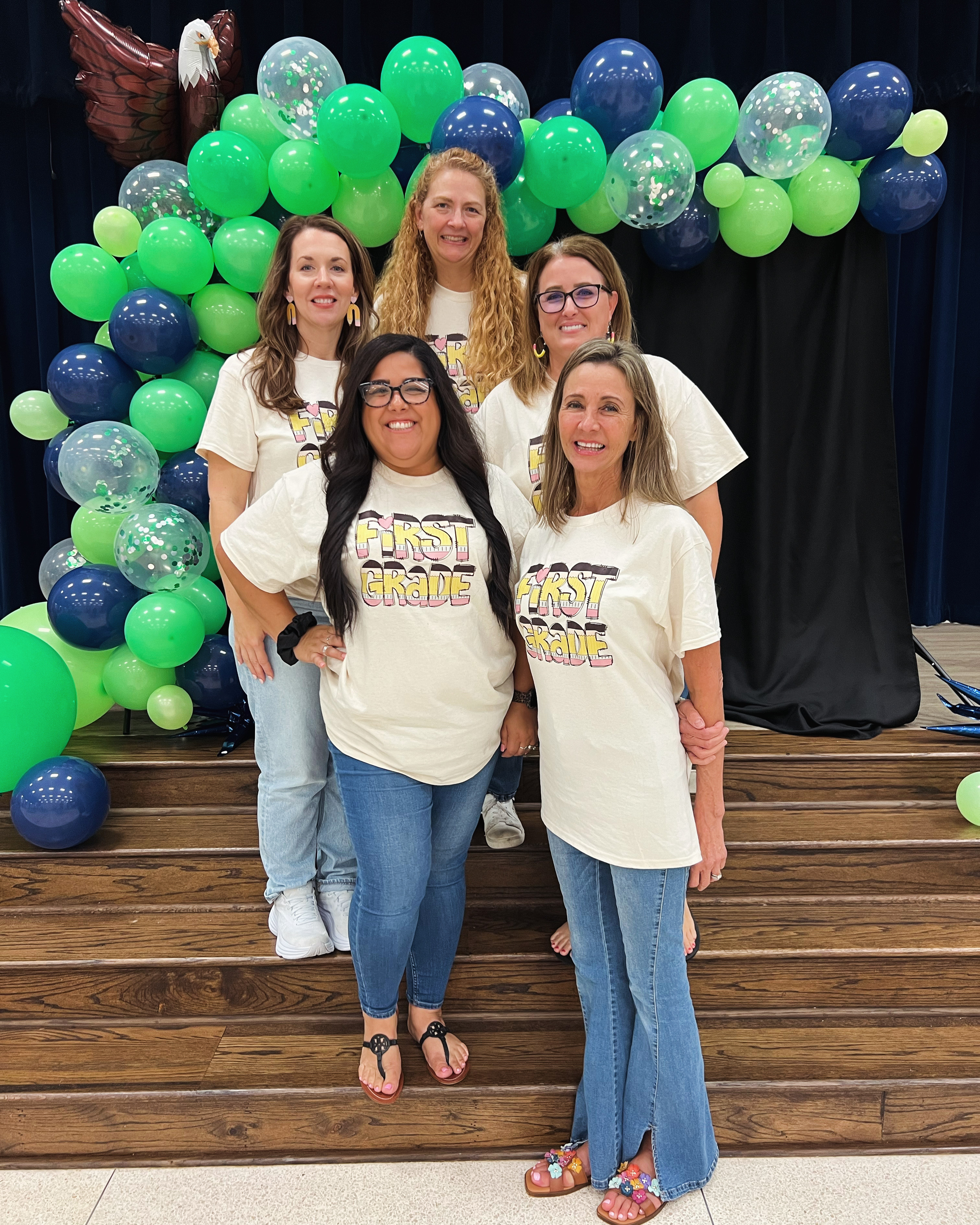 First Grade teachers in black shirts posing with balloons