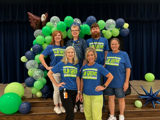 group of teachers in red shirts standing posing with balloons