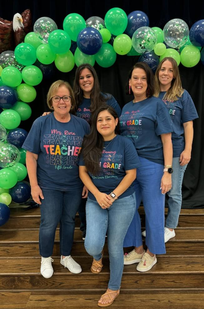 group of teachers in black shirts standing posing with balloons